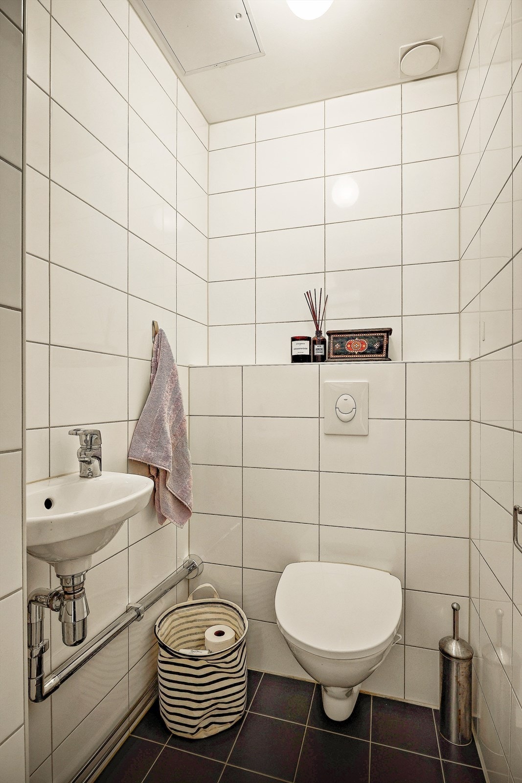 Praktisk separat toalettrom med vegghengt toalett og servant. Flislagte vegger og gulv. Galleribilde