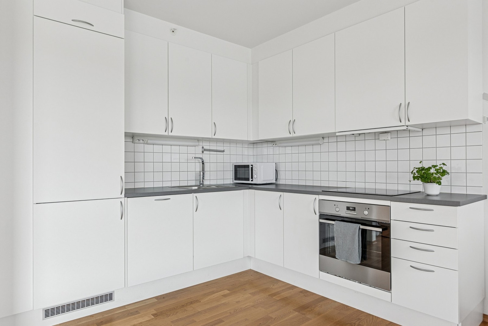 Lys kjøkkeninnredning med integrerte hvitevarer. Galleribilde