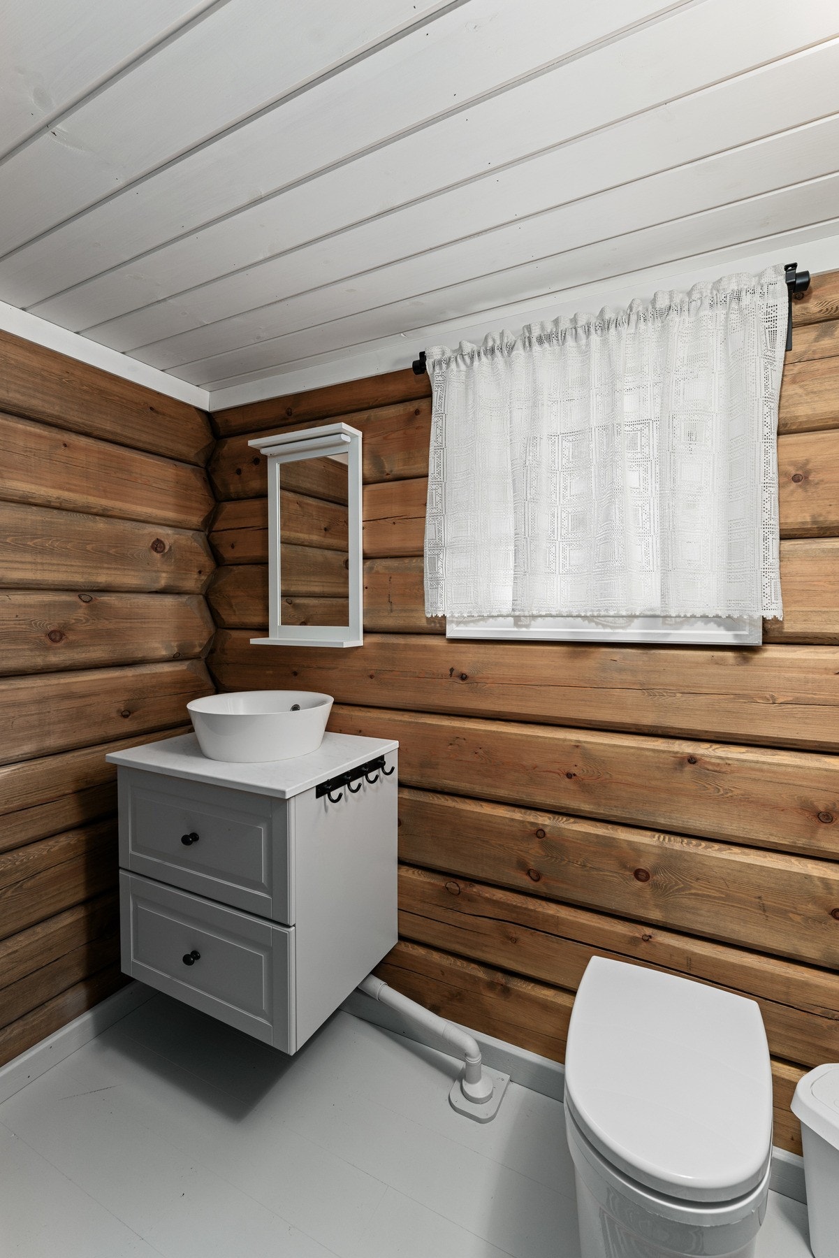 Badet er oppgradert og innredet med moderne servantinnredning uten kran, cinderellatoalett og panelte vegger i tømmer som gir et rent, rustikt uttrykk. Galleribilde