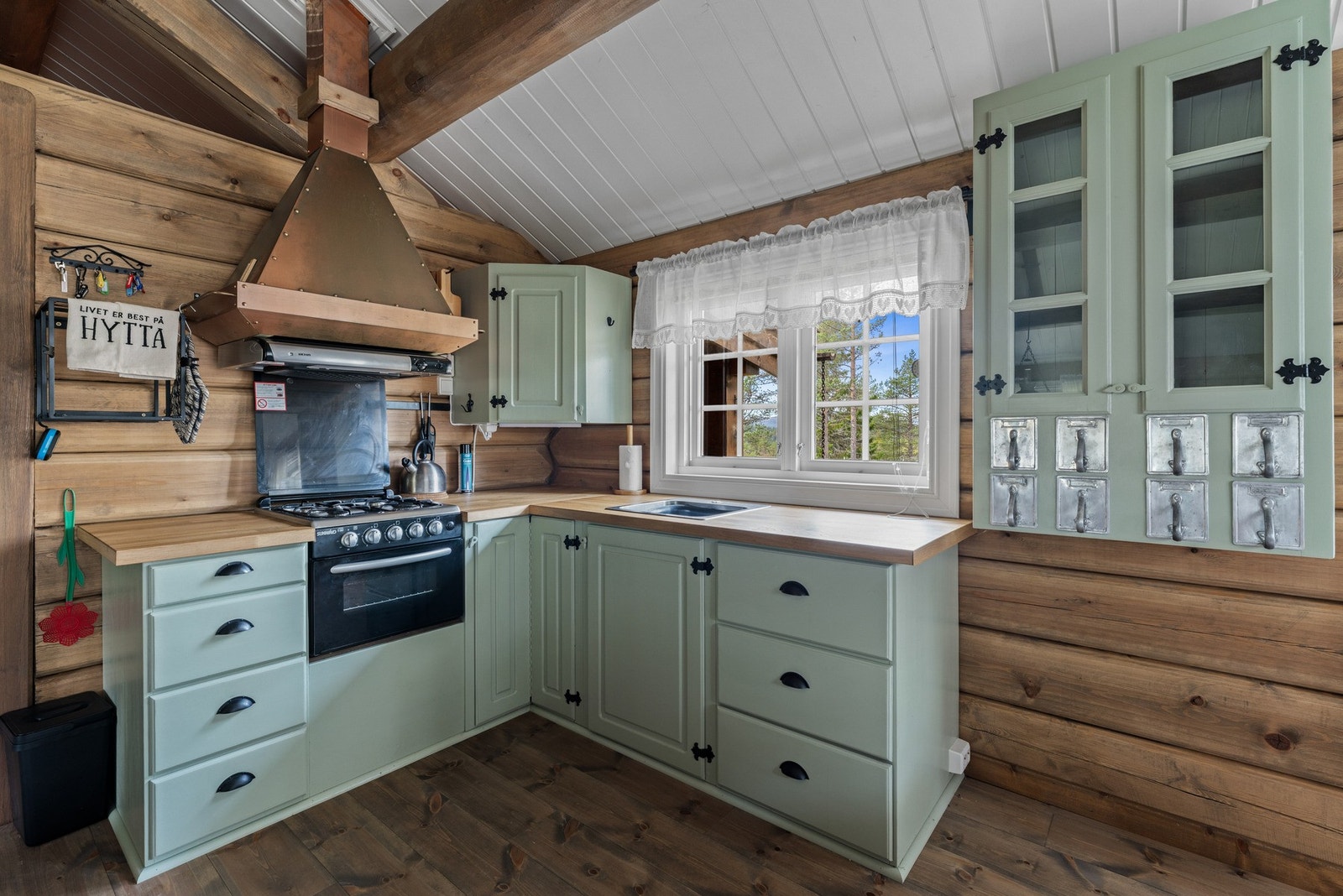Kjøkkenet er i klassisk hytteutførelse med lyse grønne fronter, heltre benkeplater og en lekker kobberfarget ventilatorhette som gir karakter. Galleribilde