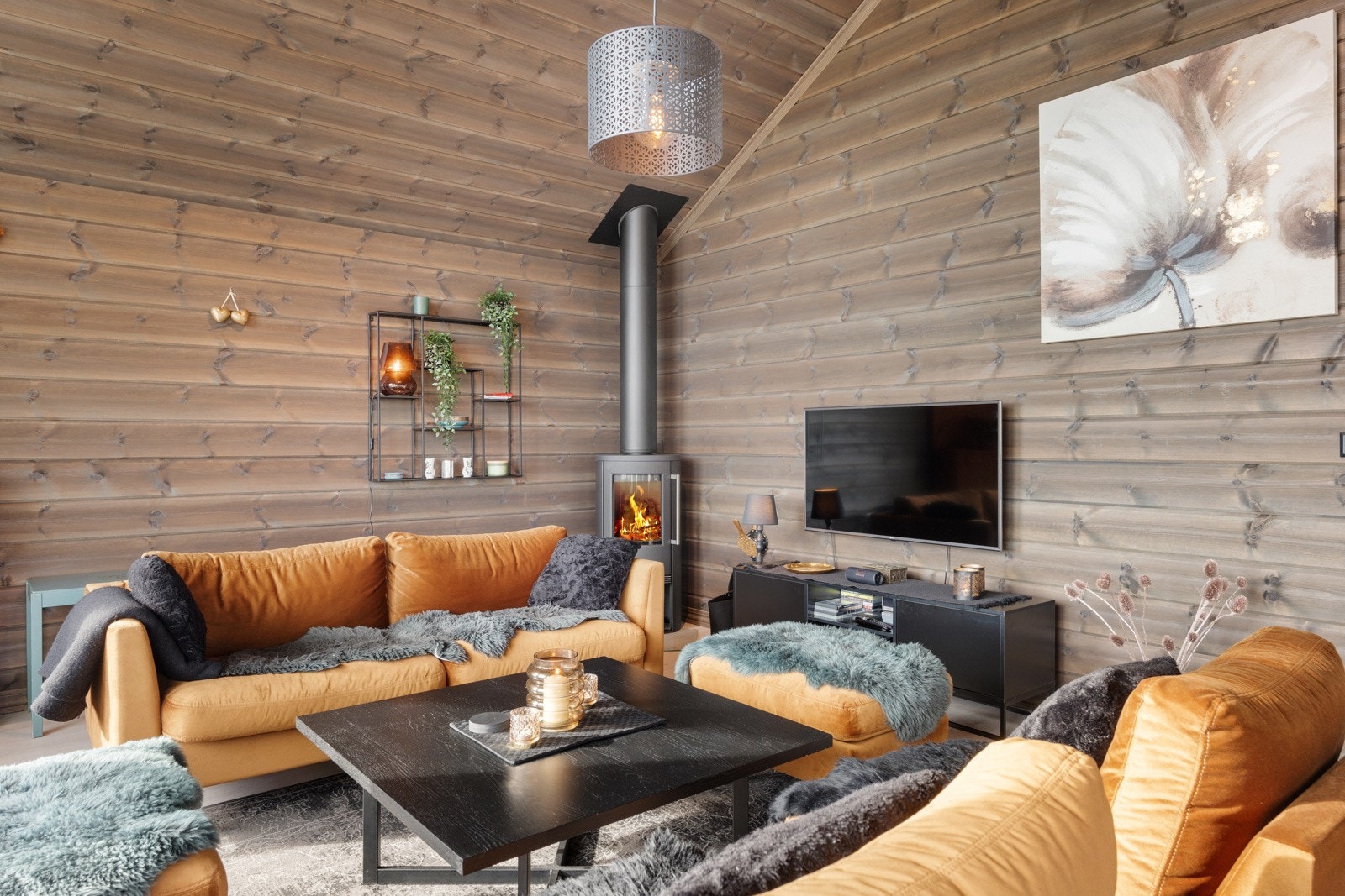 I hjørnet av stuen er det en peisovn med stål pipe som tilfører både god varme og hygge til rommet Galleribilde