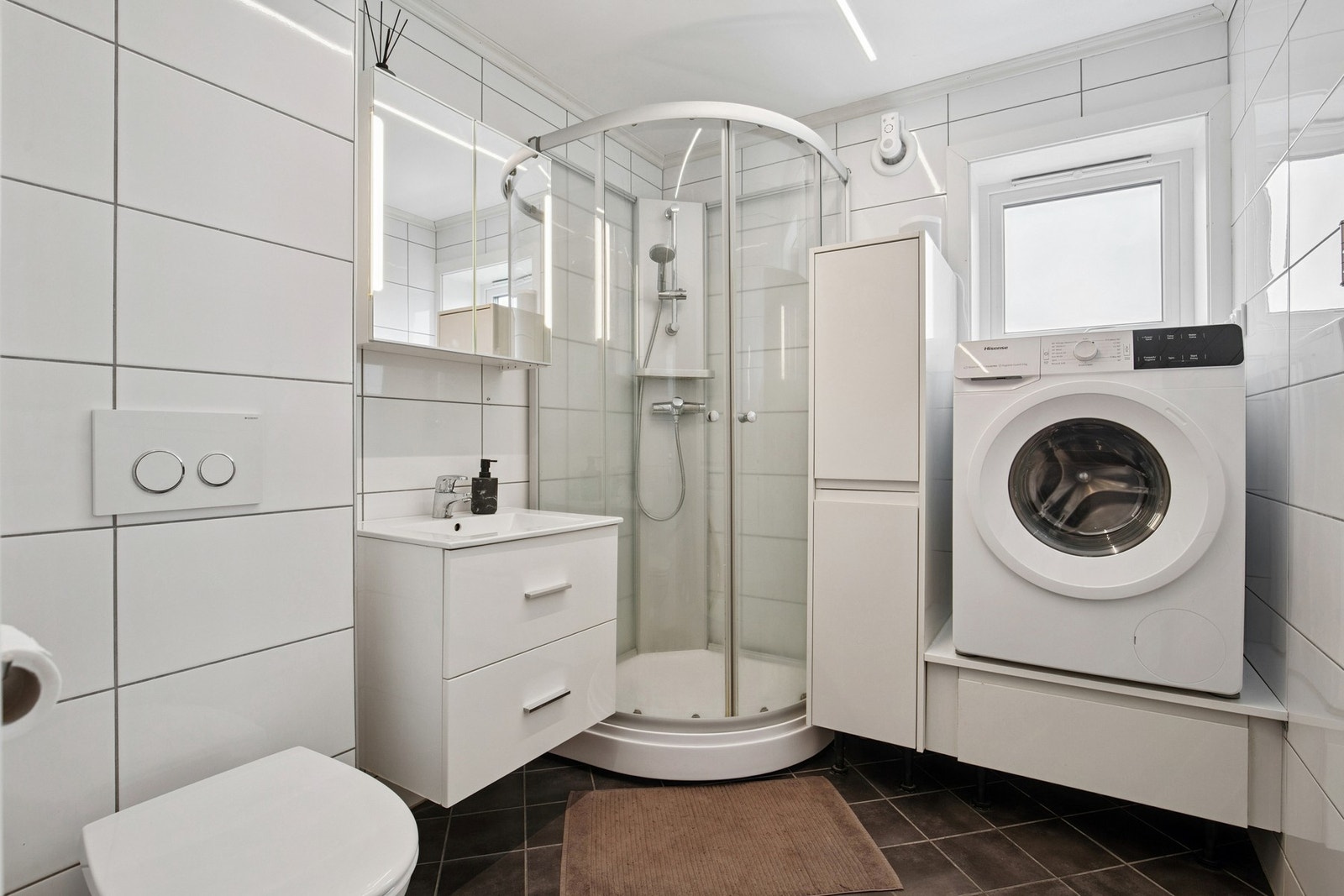 Flislagt bad , innredning m/nedfelt servant, dusjkabinett, vegghengt wc og opplegg for vaskemaskin Galleribilde