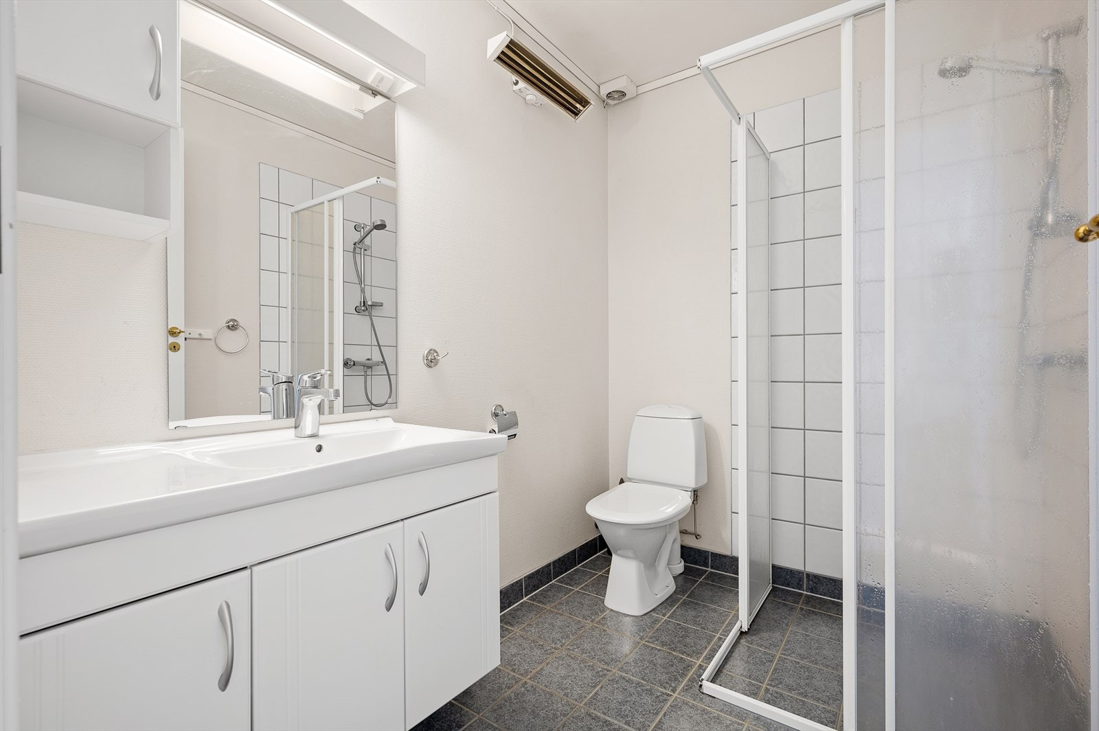 Badet er flislagt og innehar dusj, wc og servant med underskap og speil. Galleribilde