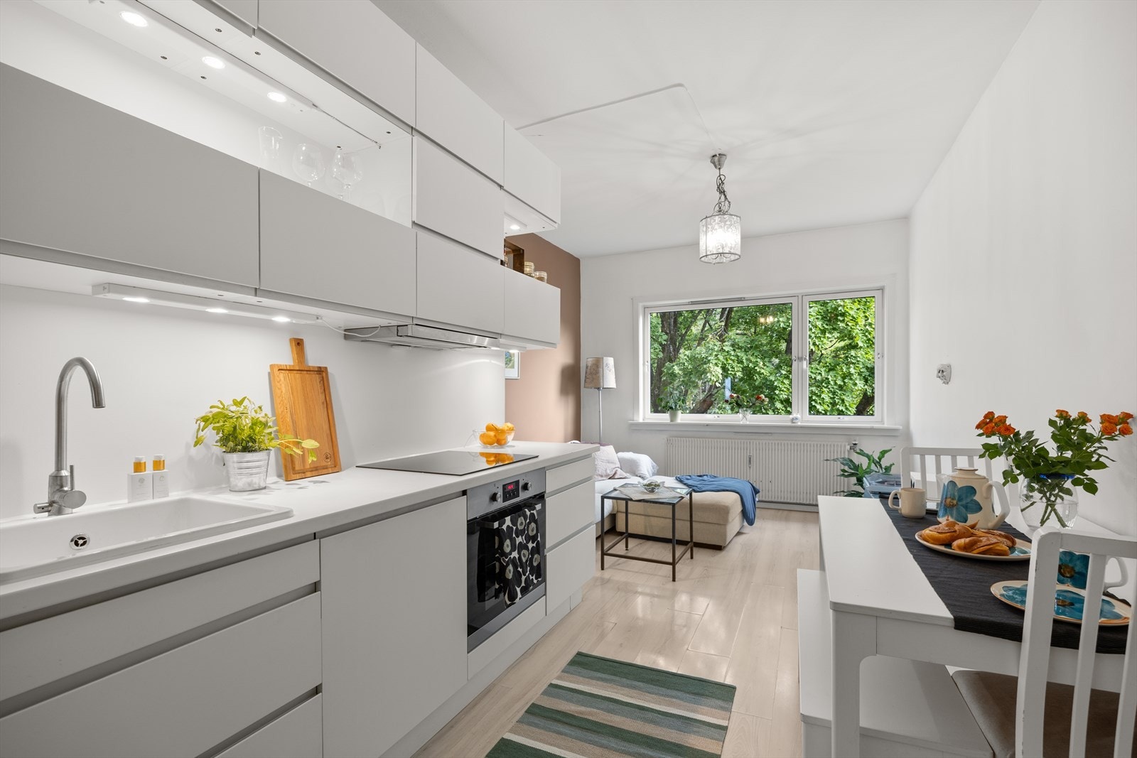 Kjøkkenet ligger i en åpen løsning med stilren IKEA-innredning fra 2013 med hvite glatte fronter og laminert benkeplate. Induksjonsplate og komfyrvakt ble installert i 2024. Galleribilde