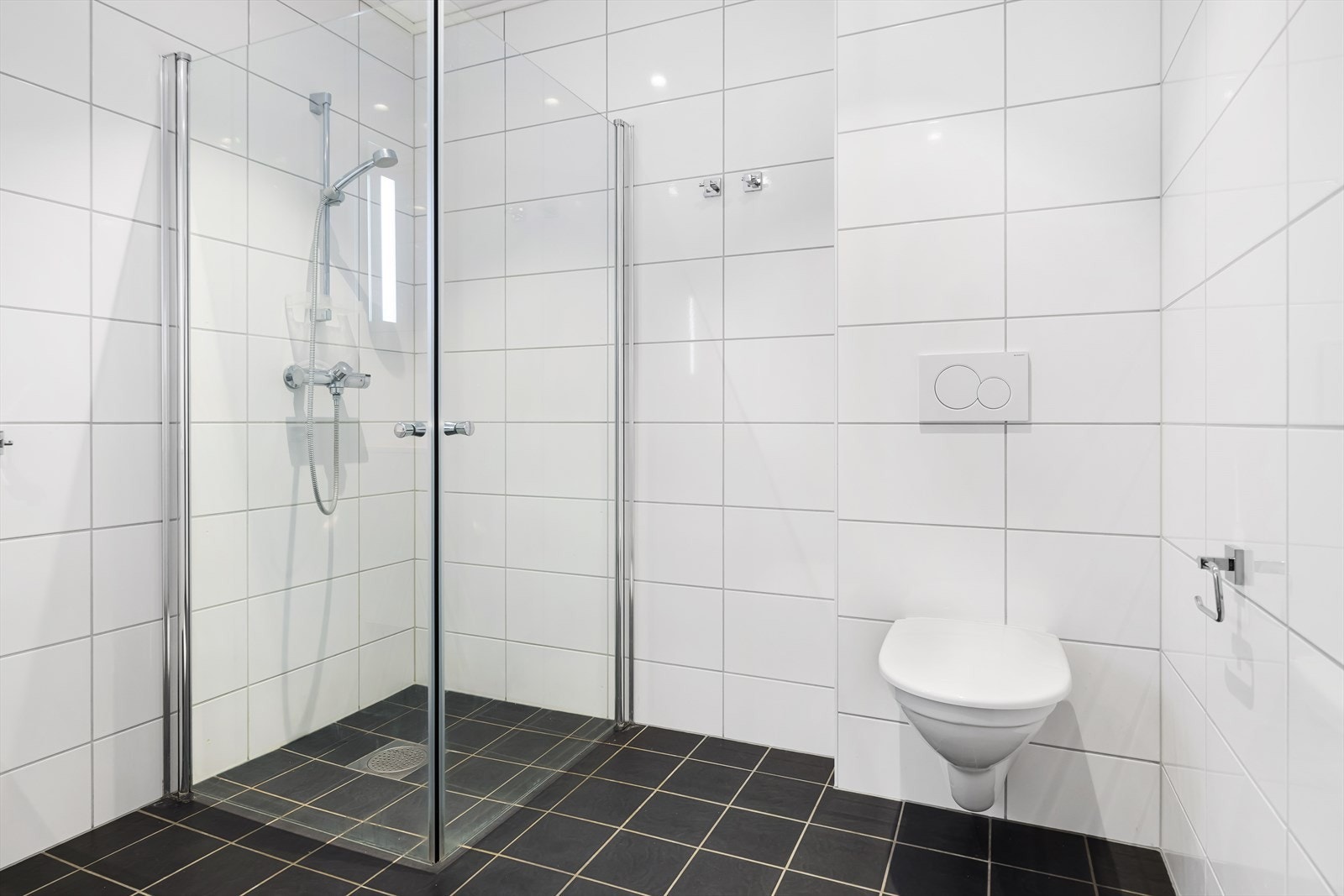 Rommet er helfliset med varme i gulvet. Mørke fliser på gulv og lyse på veggene. Galleribilde