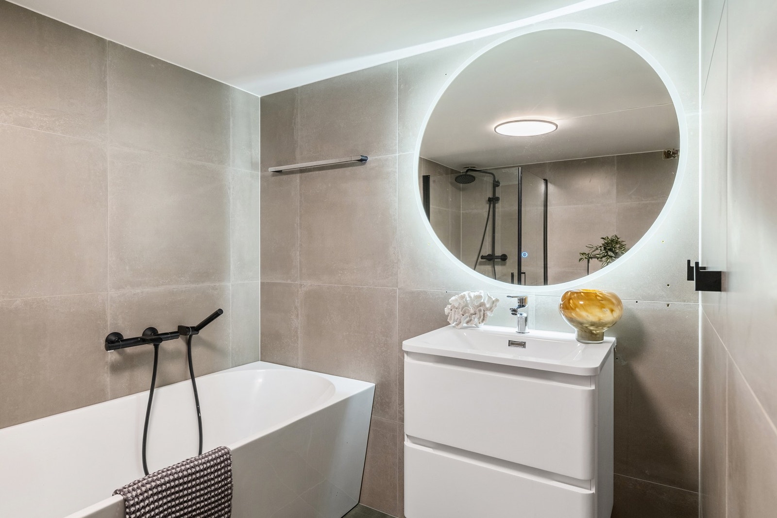 Her får du lekre fliser, pen innredning, stort speil med smart belysning og badekar! Galleribilde