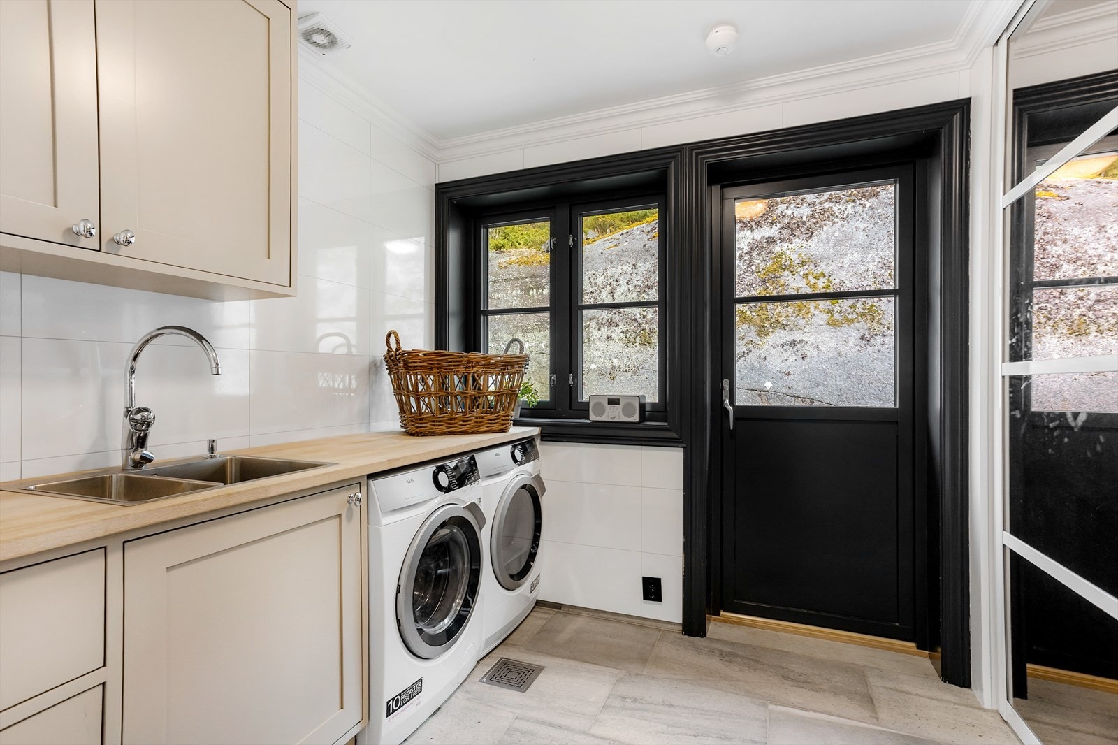 Skiferfliser og innredning tilpasset vaskemaskin, tørketrommel og benk. Herfra er det utgang til hagen. Galleribilde