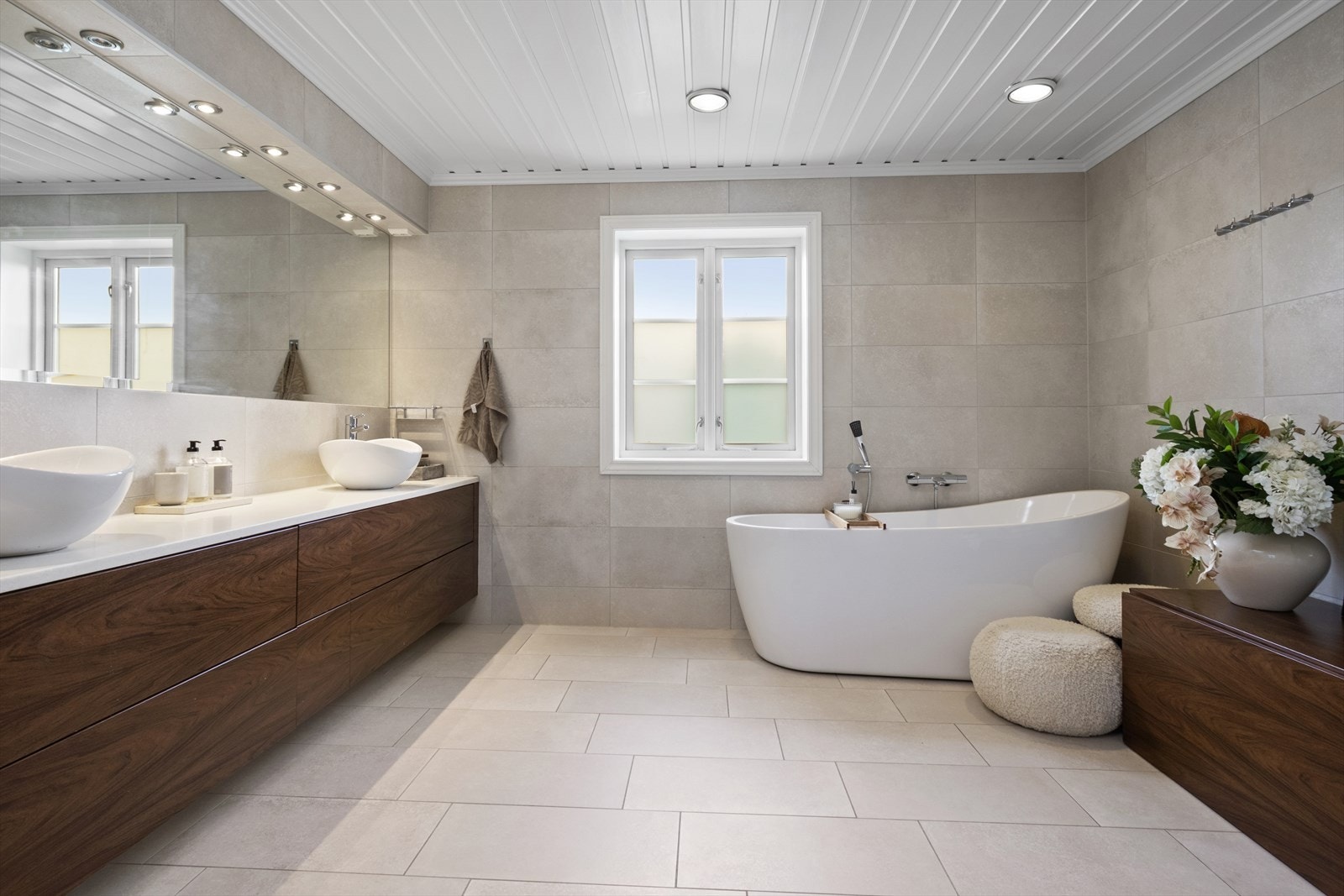 Badet har fliser på gulv med gulvvarme, flislagte vegger og malt panel i innvendig tak. Galleribilde