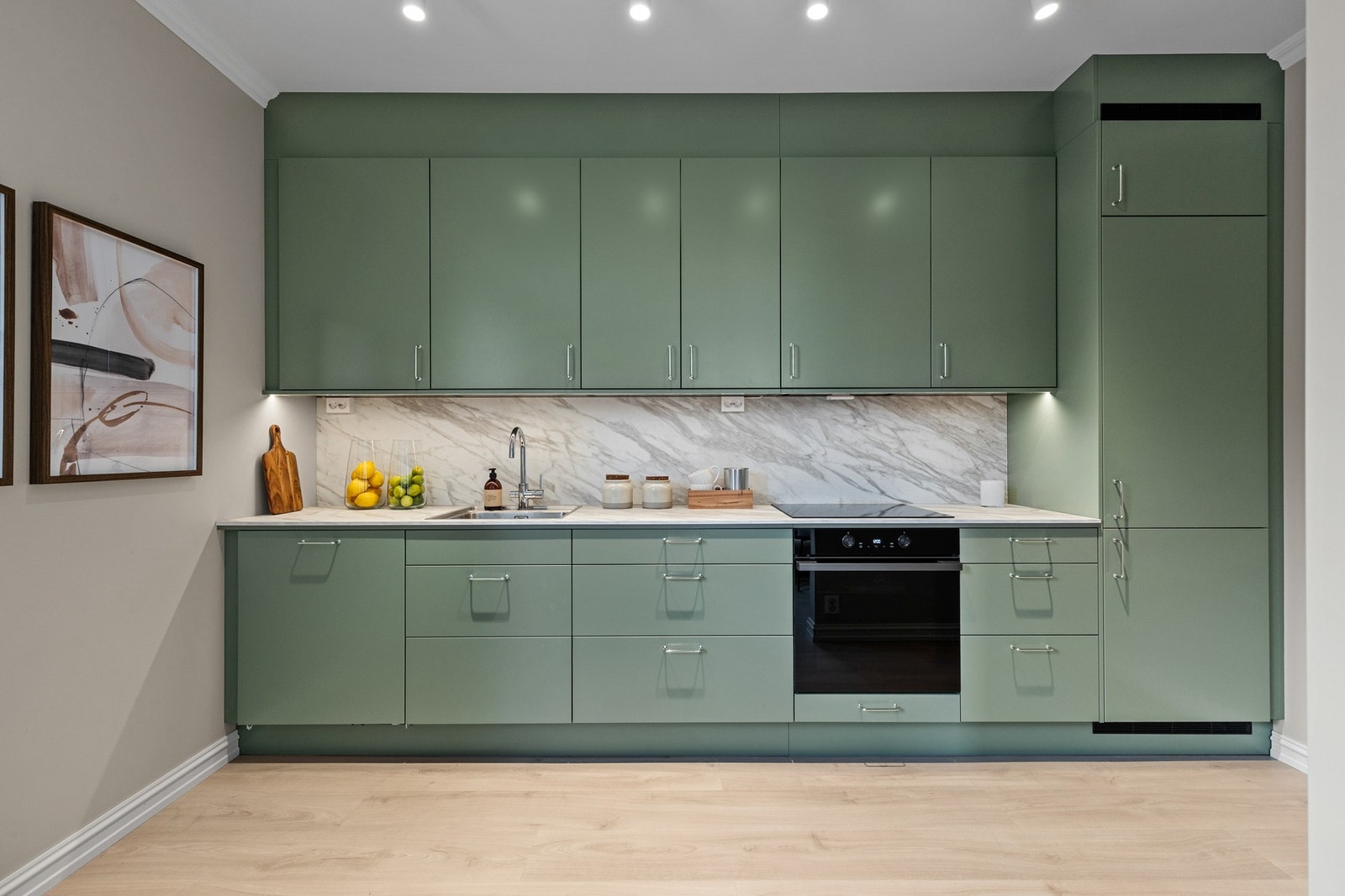 Innredningen har integrerte hvitevarer, herunder kjøl/fryseskap, oppvaskmaskin, induksjonstopp og stekeovn Galleribilde