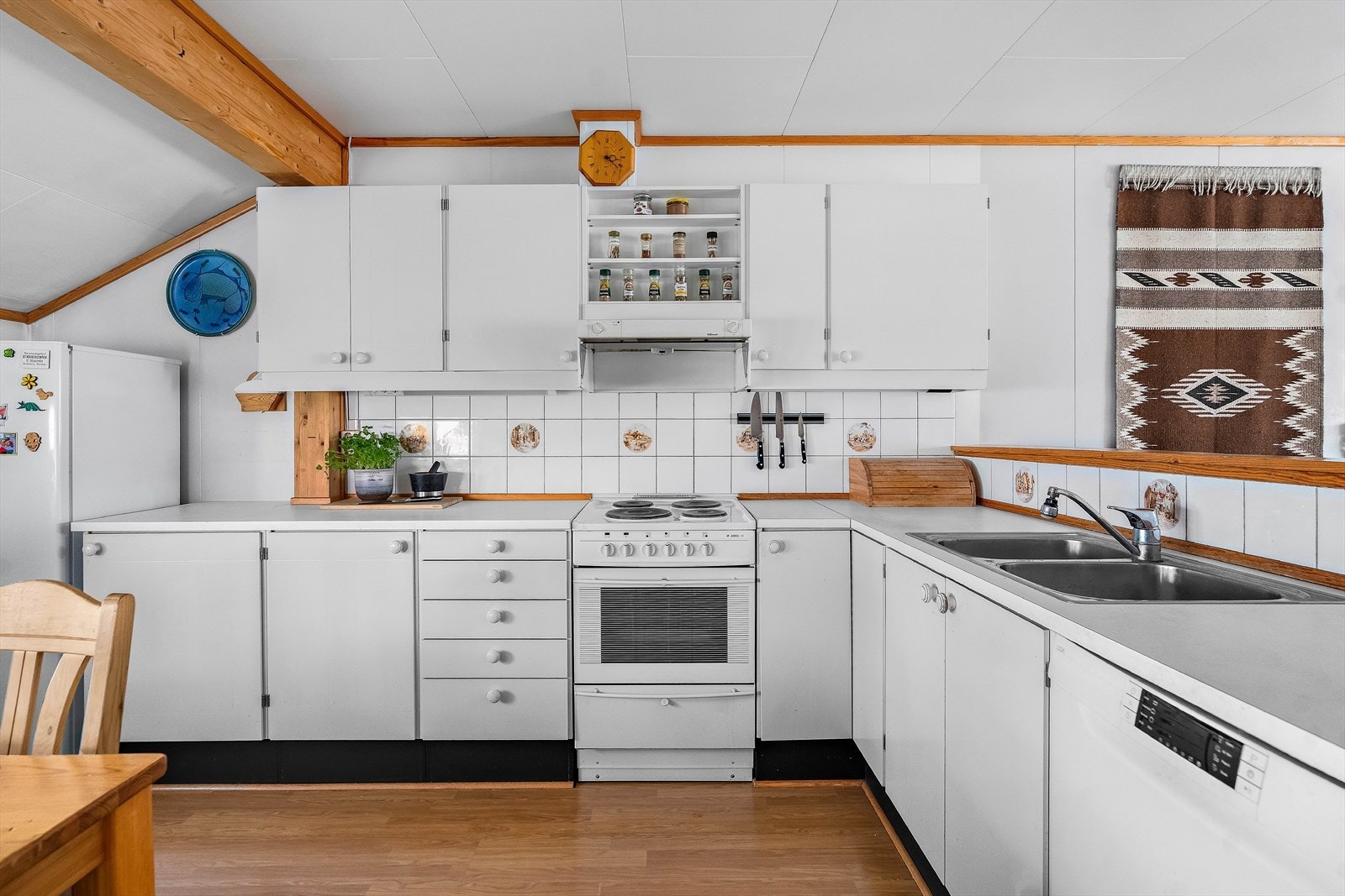 Lyst kjøkken i delvis åpen løsning. Halvveggen sikrer godt med lysinnslipp fra to himmelretninger. Galleribilde