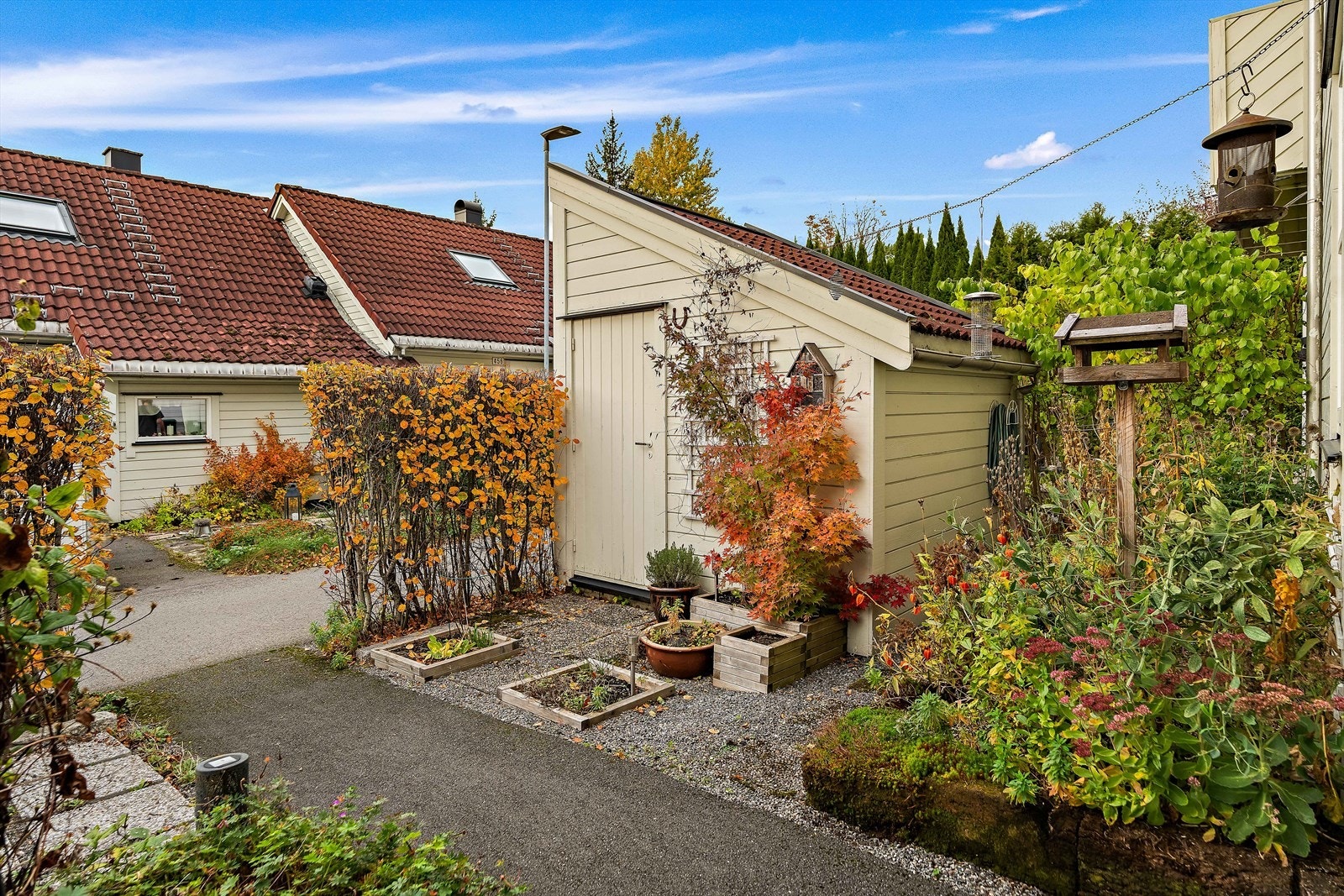 Ved inngangspartiet er det en utebod for hageredskapene. Det er hellelagt og grusganger mellom beplantningen for enkel adkomst. Galleribilde