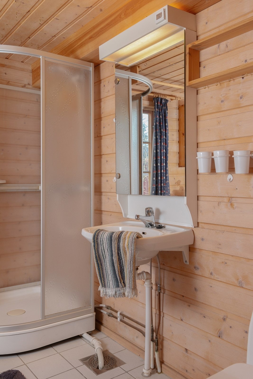 Dette badet er innredet med servant, speilskap med belysning, dusjkabinett, gulvmontert toalett og opplegg for vaskemaskin. Galleribilde