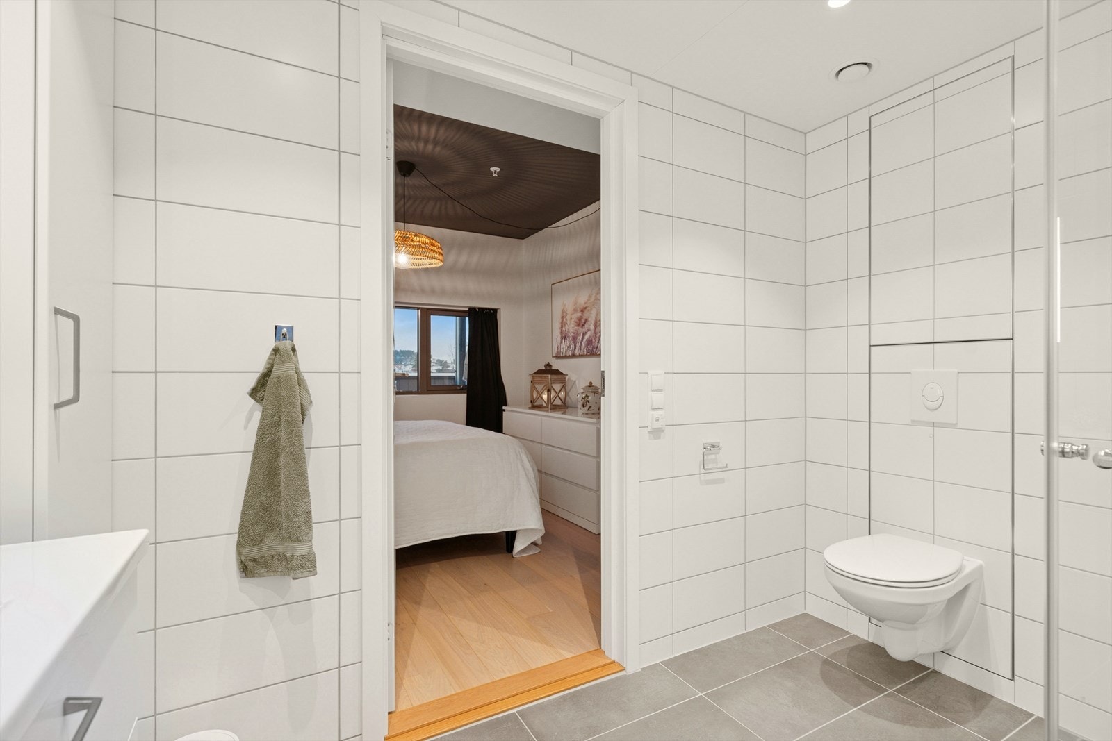 Badet er pent flislaget med store, grå fliser på gulvet og hvite fliser på vegger. Galleribilde