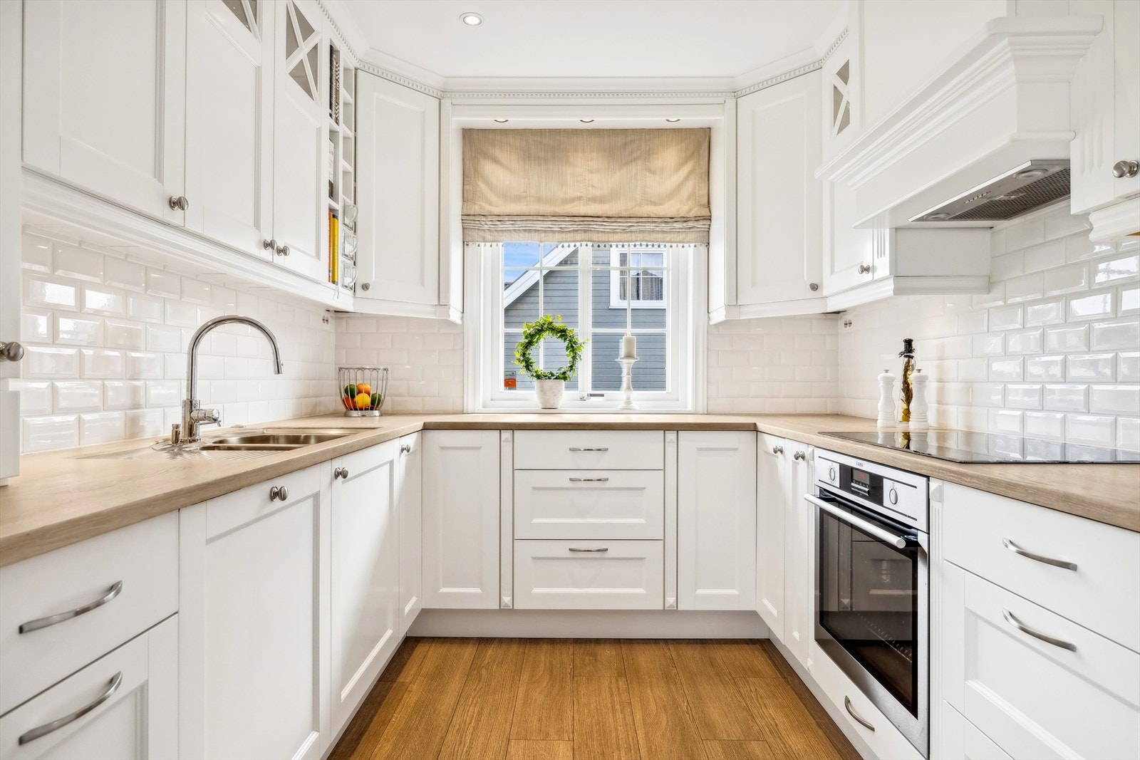 Kjøkkenet har en innredning fra Strai med hvite profilerte dør- og skuffronter, skiftet i 2014. Benkeplate i heltre oljet eik. Galleribilde