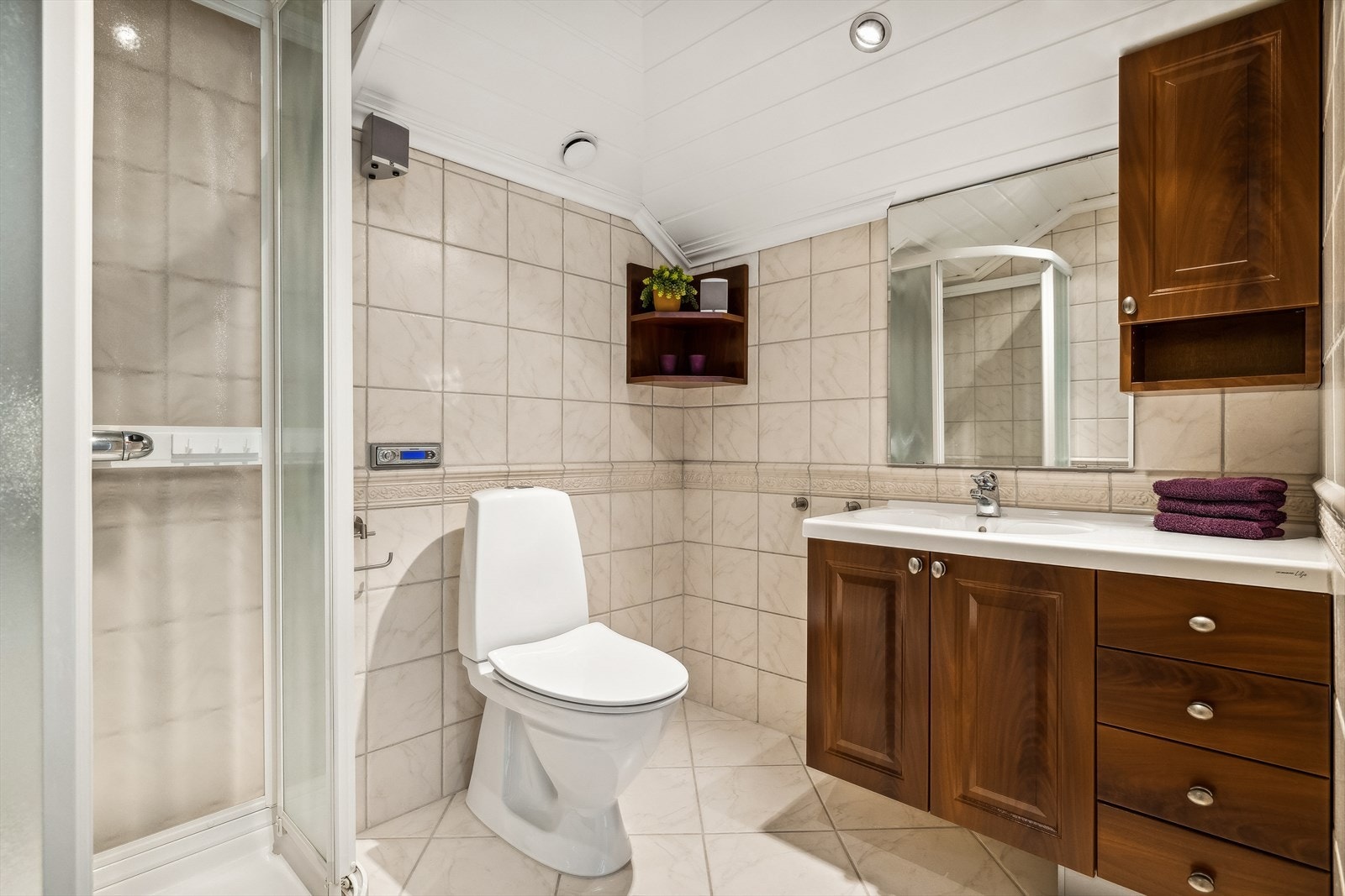 Baderom i andre etasje med fliser på gulv og vegg. Dusjkabinett og gulvmontert toalett. Galleribilde