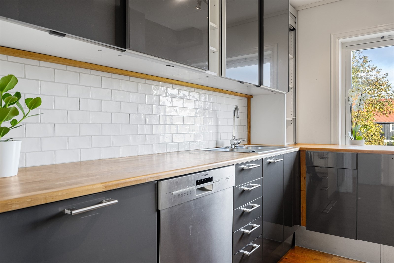 Innredningen har grå glatte fronter og laminert benkeplate med nedfelt oppvaskkum. Både fint og praktisk med lyse fliser i benkeryggen. Galleribilde