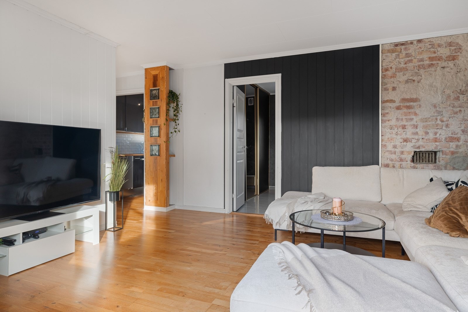 Stuen har parkett på gulv og malte panelplater på veggene kombinert med synlig teglstein som gir en lun og god atmosfære. Galleribilde