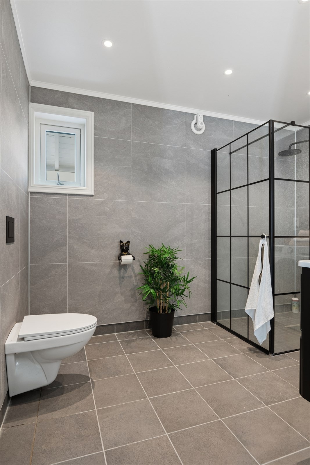 Badet har fliser på gulv med gulvvarme, våtromsplater på veggene og malte plater i himling med spotter. Galleribilde