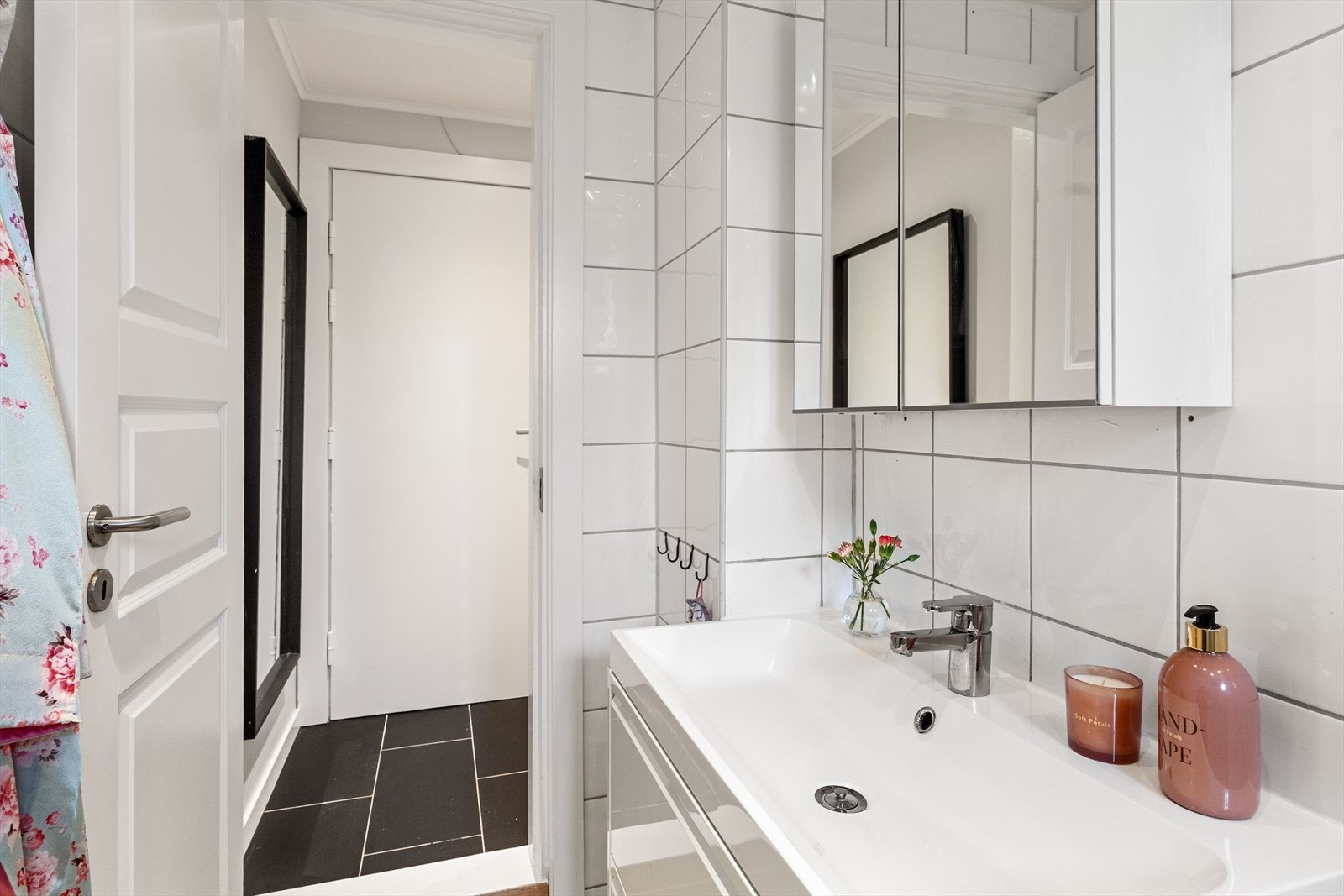 Badet inneholder veggmontert toalett, dusjhjørne med vegg/dør i herdet glass, servant med skap, speil og belysning, samt opplegg for vaskemaskin. Galleribilde