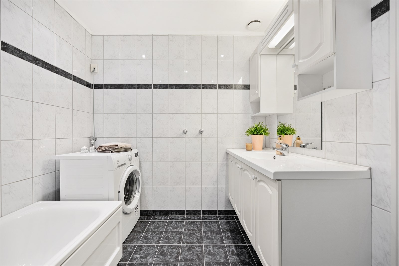 Badet er helfliset og utstyrt med servantseksjon, badekar og opplegg for vaskemaskin. Galleribilde