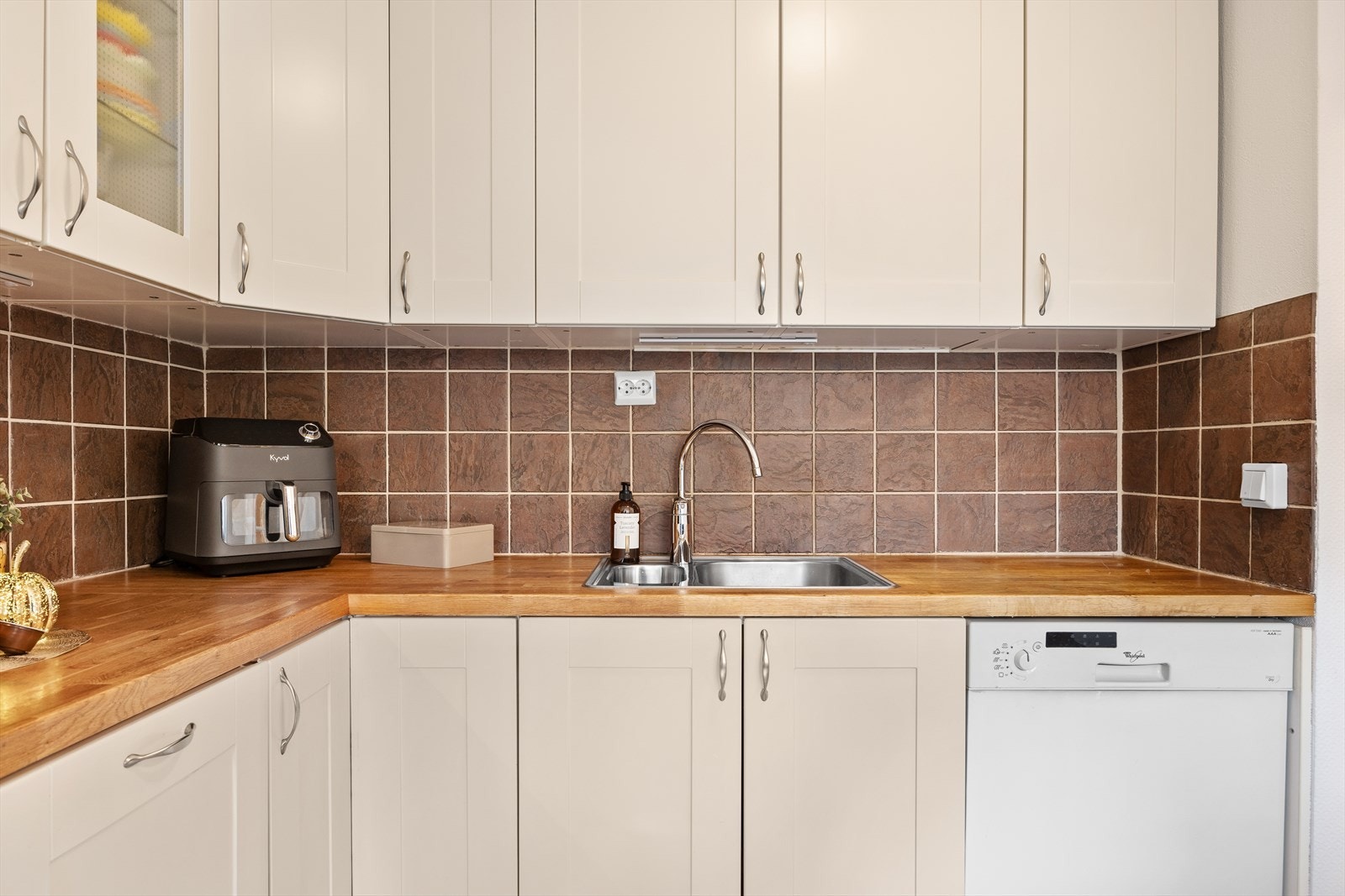 Detaljer som nedfelt oppvaskkum og fliser over benken understreker funksjonaliteten. Galleribilde