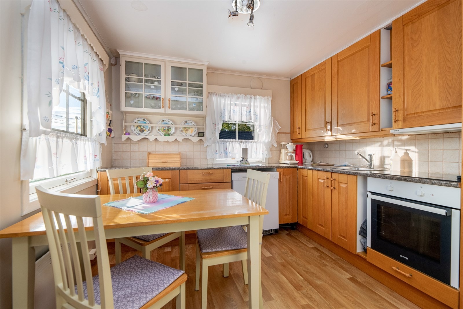 Her er det det godt med skapplass i takhøy innredning fra 1981 med heltre fronter, samt at det er gode arbeidsflater på laminerte benkeplater. Det er også plassbygget et sjarmerende skap på veggen, med glassdører og tallerkenhylle. Galleribilde