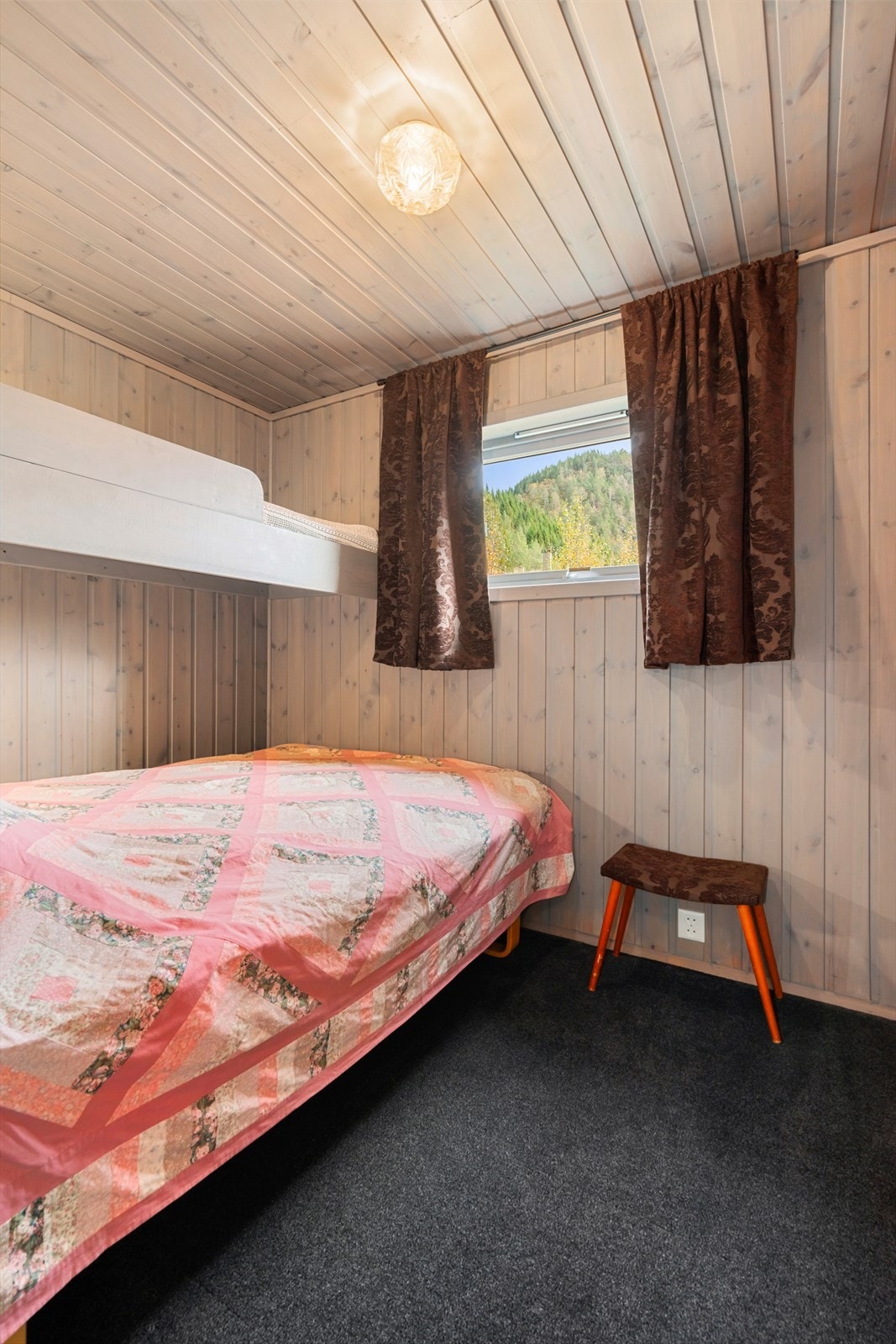 Soverom med lys panel på veggene og en praktisk køyseng for ekstra sengeplasser. Galleribilde