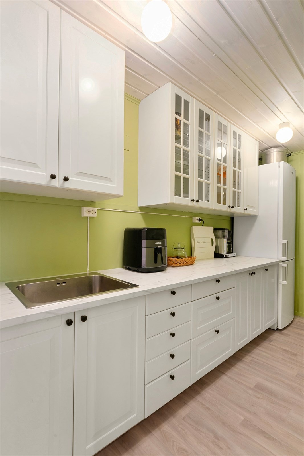 Spisskammeret har hvite skap med profilerte fronter og laminat benkeplate. Galleribilde