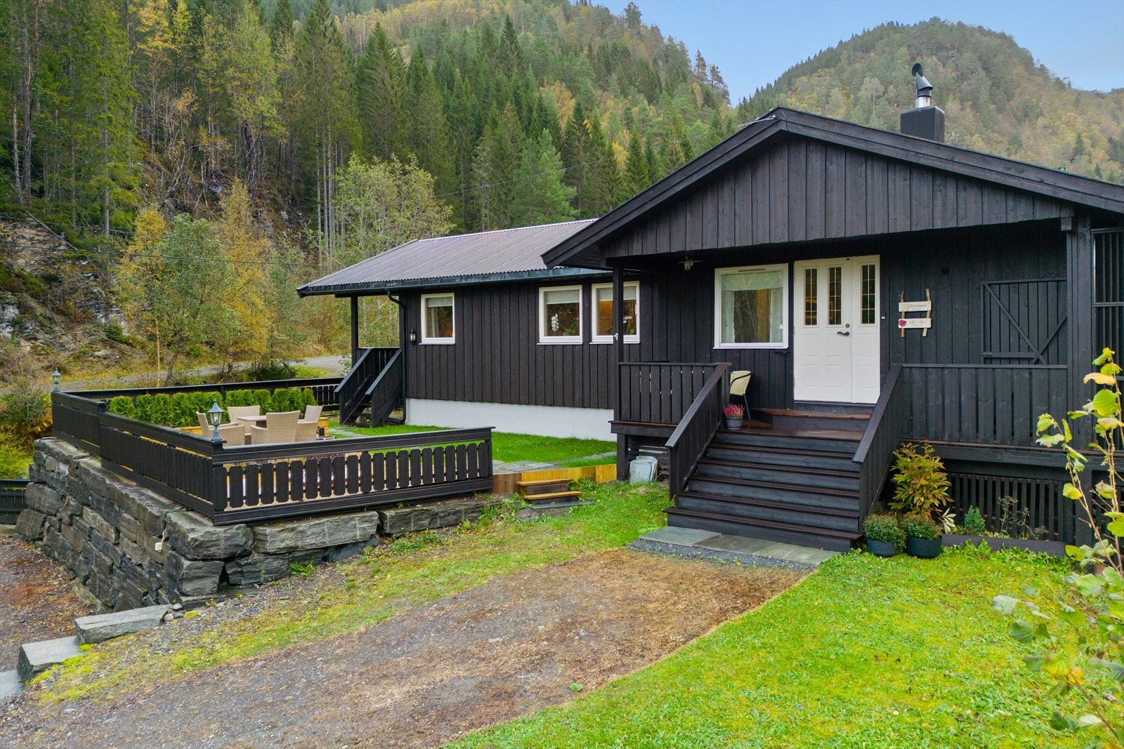 Inngangspartiet har en profilert ytterdør med vindusfelt og en tretrapp med tette opptrinn. Galleribilde