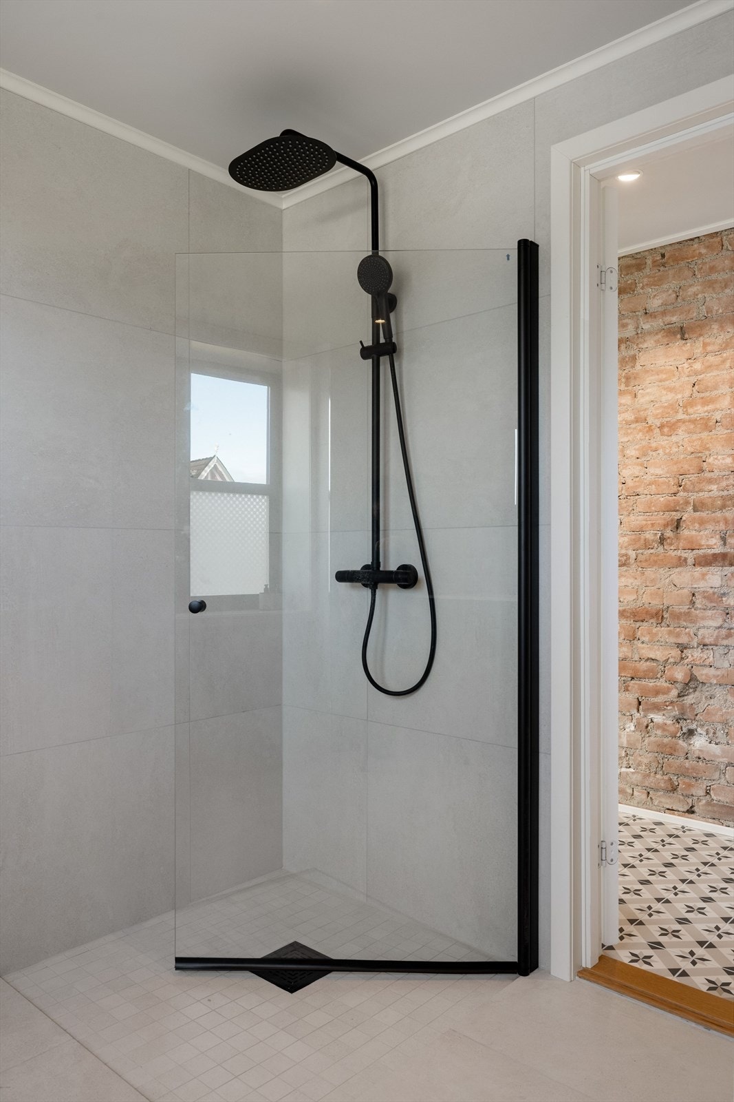 Dusjhjørne med innfellbar dusjdør og vegghengt dusjbatteri med regnfall. Galleribilde