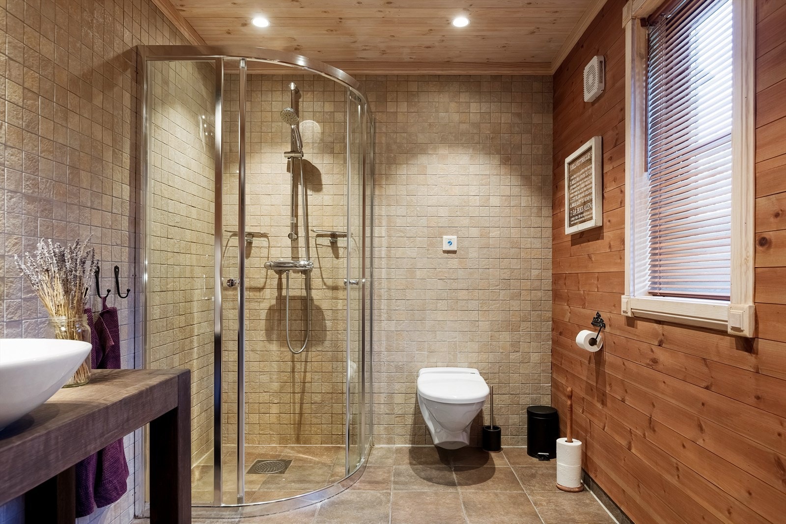 Bad med en kombinasjon av fliser og panel på overflater. Badet er innredet med servant, dusj og toalett. Galleribilde