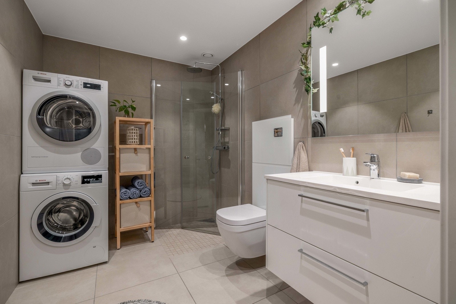 Fliser på gulv og vegger. Innfelt belysning i tak. Praktisk innredning med heldekkende servant og lagring i kolonialskuffer Galleribilde