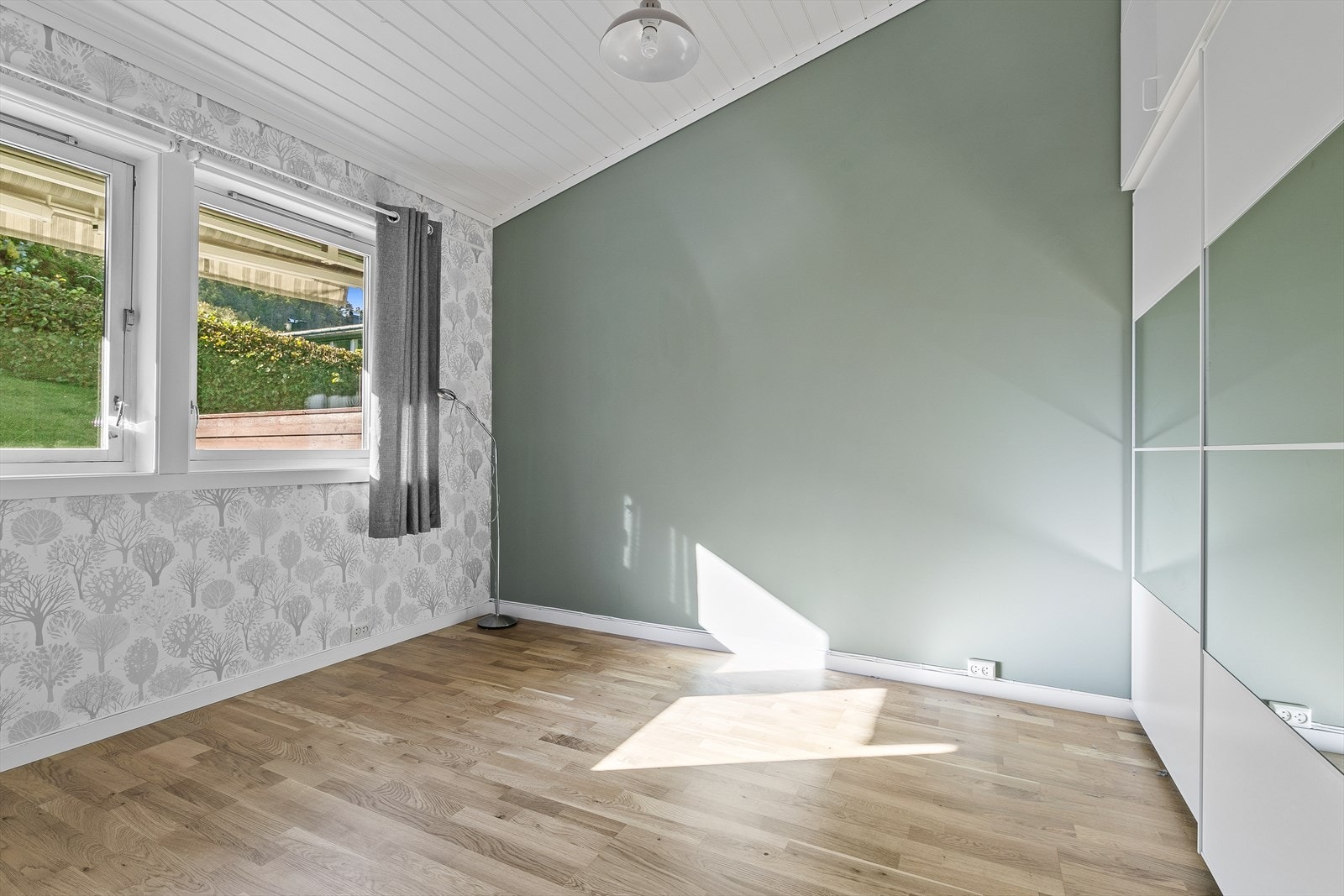 Til sist er det et soverom innenfor stua, med parkett på gulv, tapet/malte plater på vegger og malt panel i himling. Galleribilde