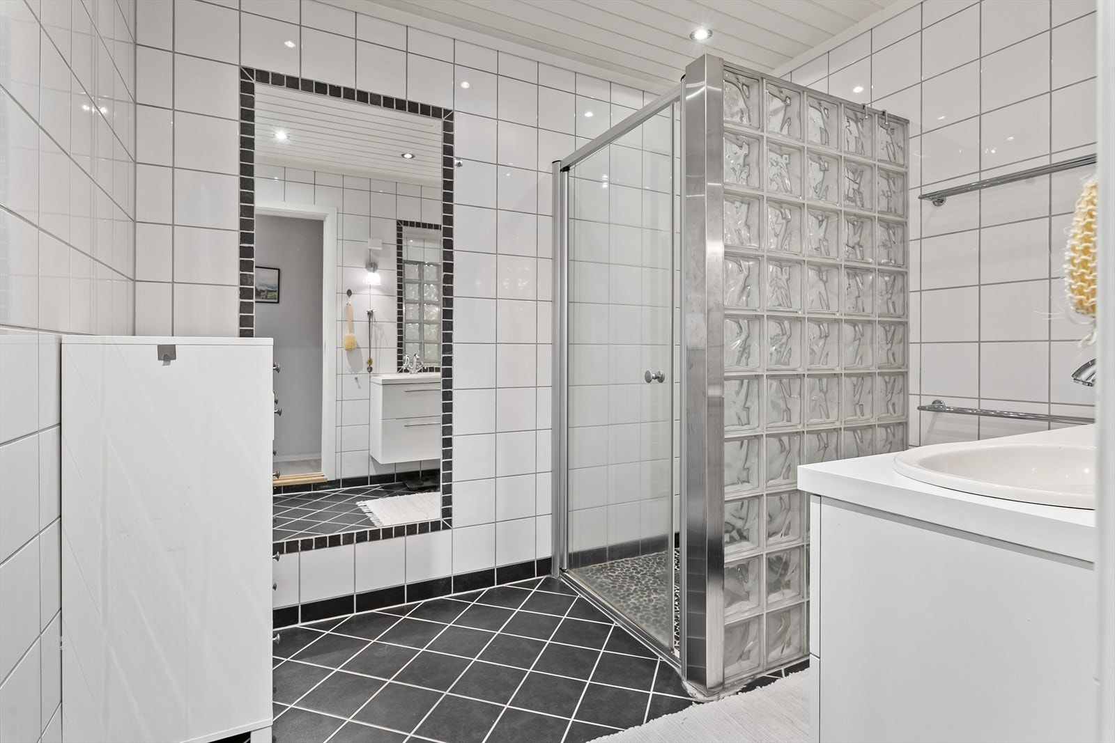 Badet inneholder dusjhjørne og servant, og har i tillegg spotter i himling. Galleribilde