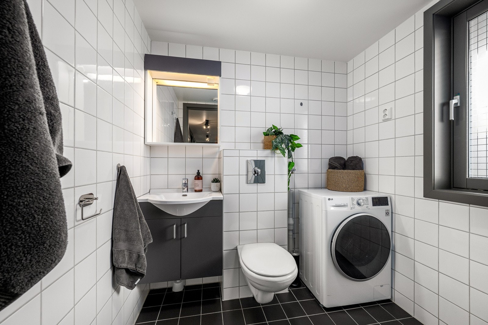 Leiligheten har et flislagt bad som inneholder baderomsinnredning, vegghengt wc, dusj og opplegg for vaskemaskin. Galleribilde