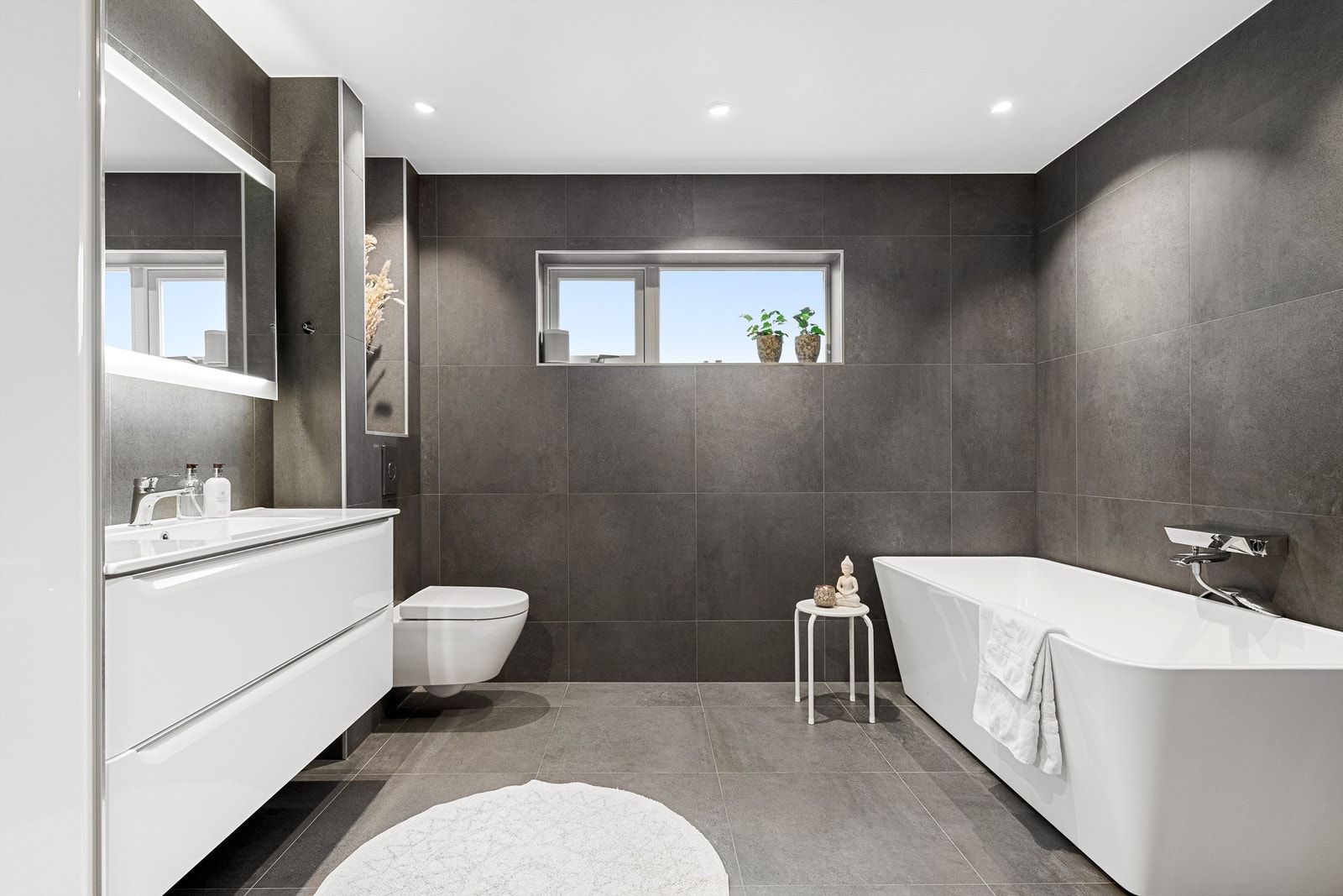 Flott flislagt bad fra 2018 i tilbygget del i underetasjen. Store 60x60 fliser på gulv og vegger. Frittstående badekar med vegghengt badekarsarmatur Galleribilde