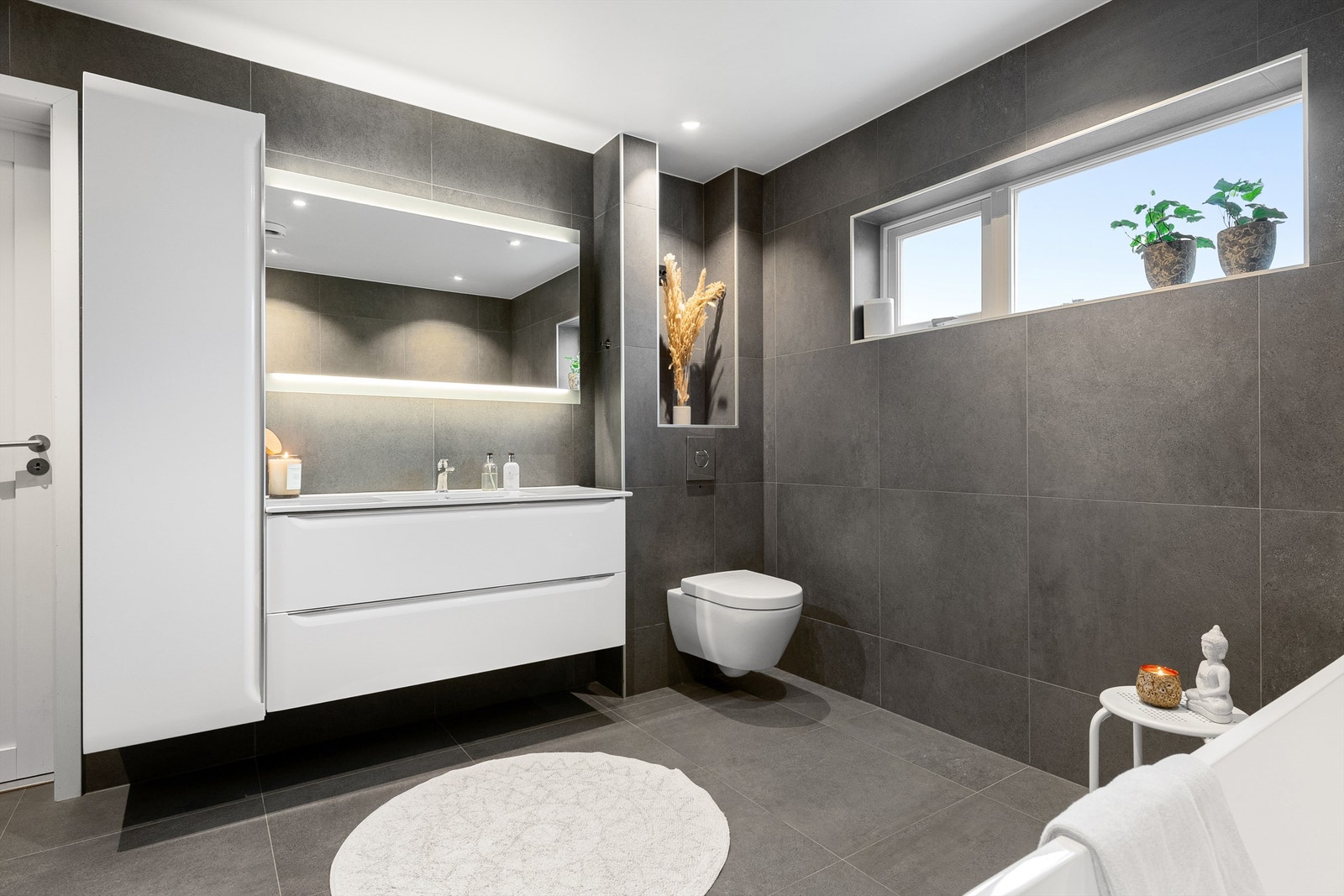 Stor baderomsinnredning med ovenpåliggende servant. Speil med lys. Vegghengt wc Galleribilde