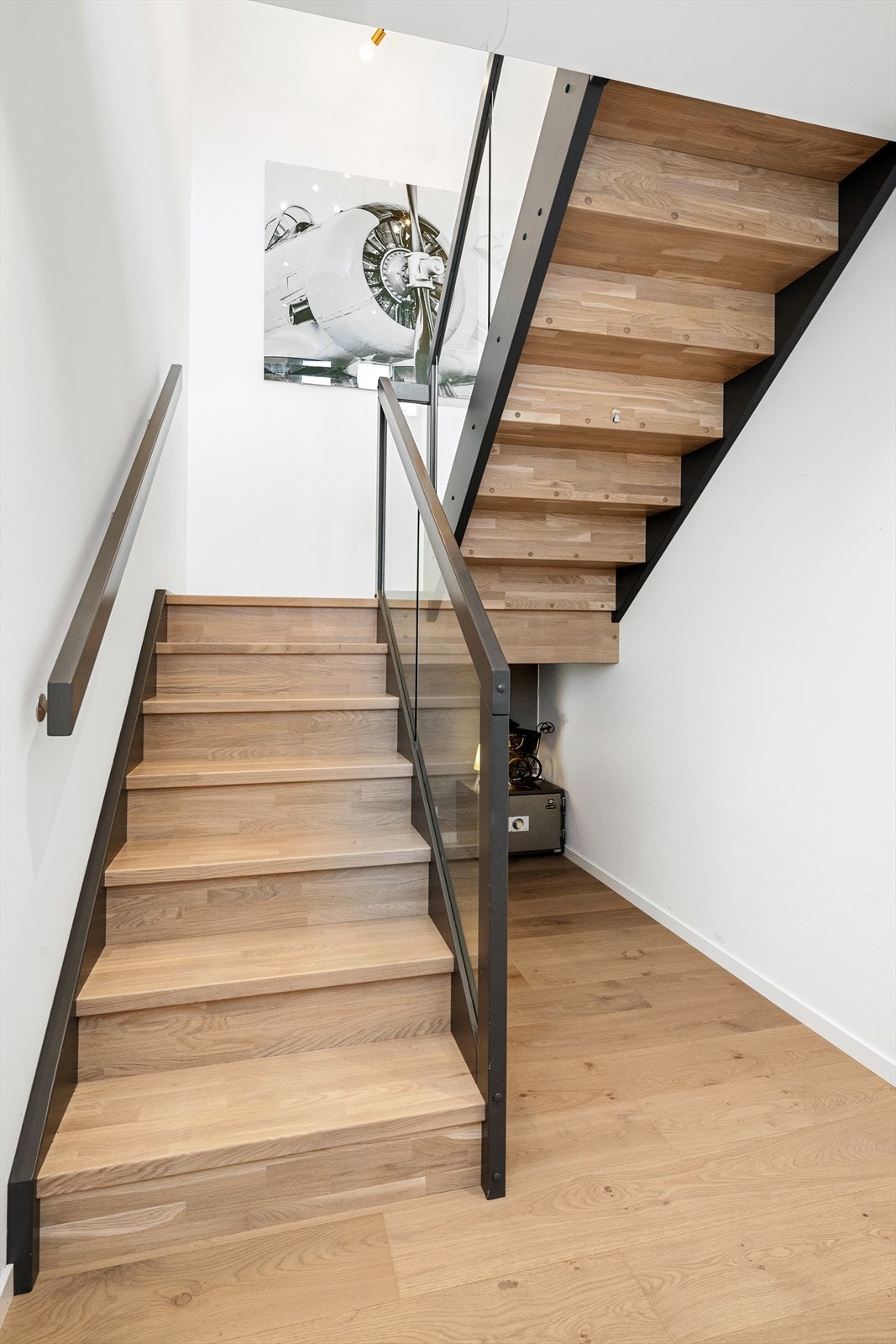 Gang/trapperom i underetasjen med flott innvendig trapp i tre med rekkverk av glass og metall Galleribilde