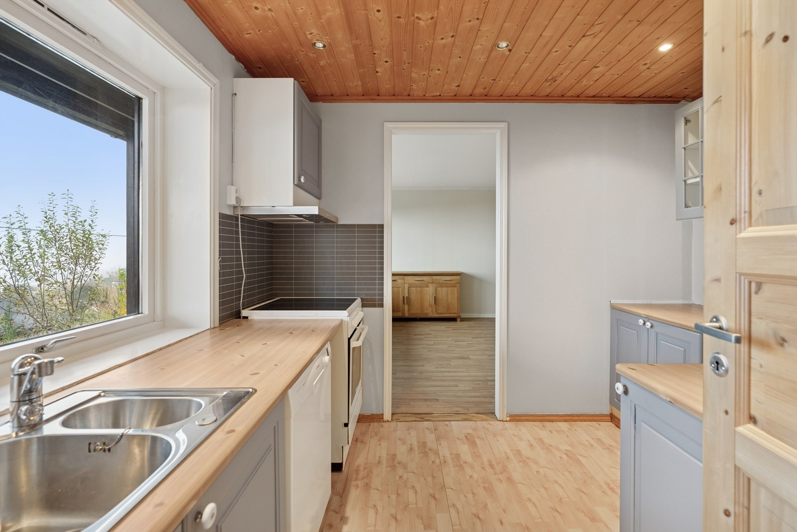 Kjøkkeninnredning av eldre årgang med malte profilerte fronter og laminert benkeplate. Galleribilde