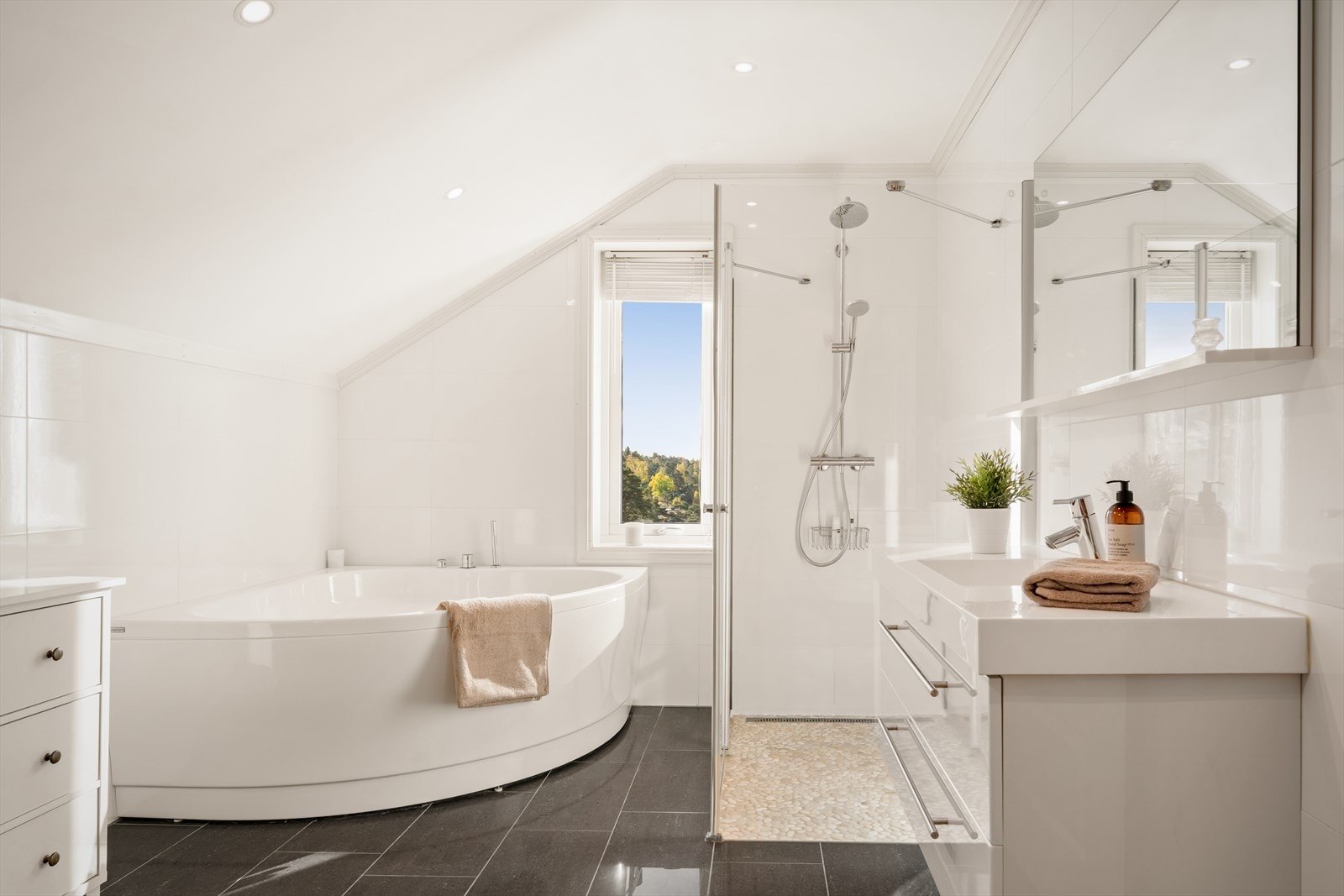 Badet består av servant med innredning, badekar, hjørnedusj og vegghengt klosett. Galleribilde