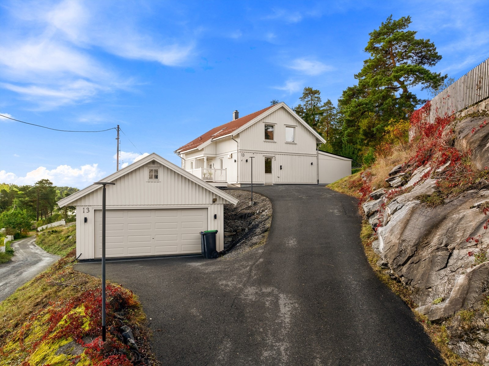 Asfaltert gårdsplass. Garasje med hems. Galleribilde