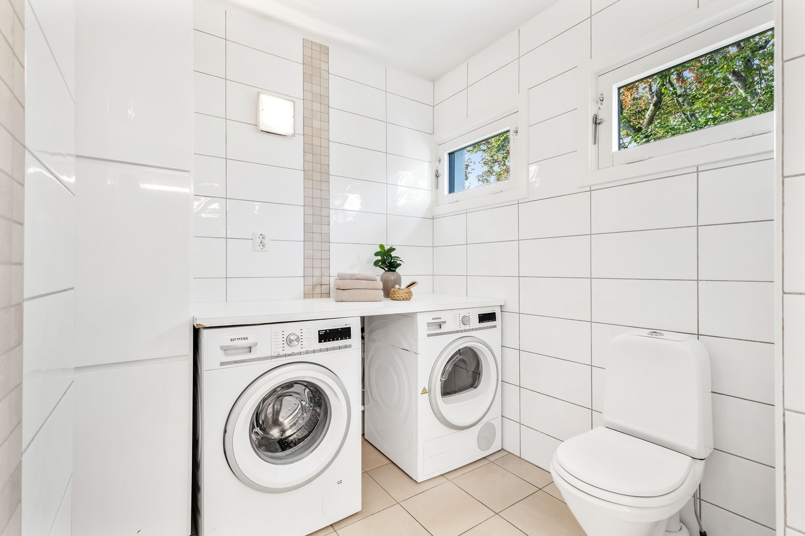 Badet er utstyrt med gulvstående toalett, innredning med nedfelt servant og opplegg for vaskemaskin og tørketrommel Galleribilde