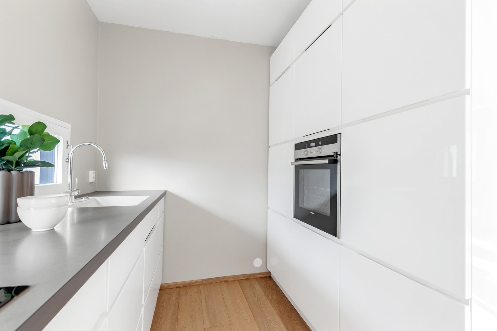 Innredningen har integrerte hvitevarer, herunder kjøleskap, oppvaskmaskin, induksjonstopp og stekeovn Galleribilde