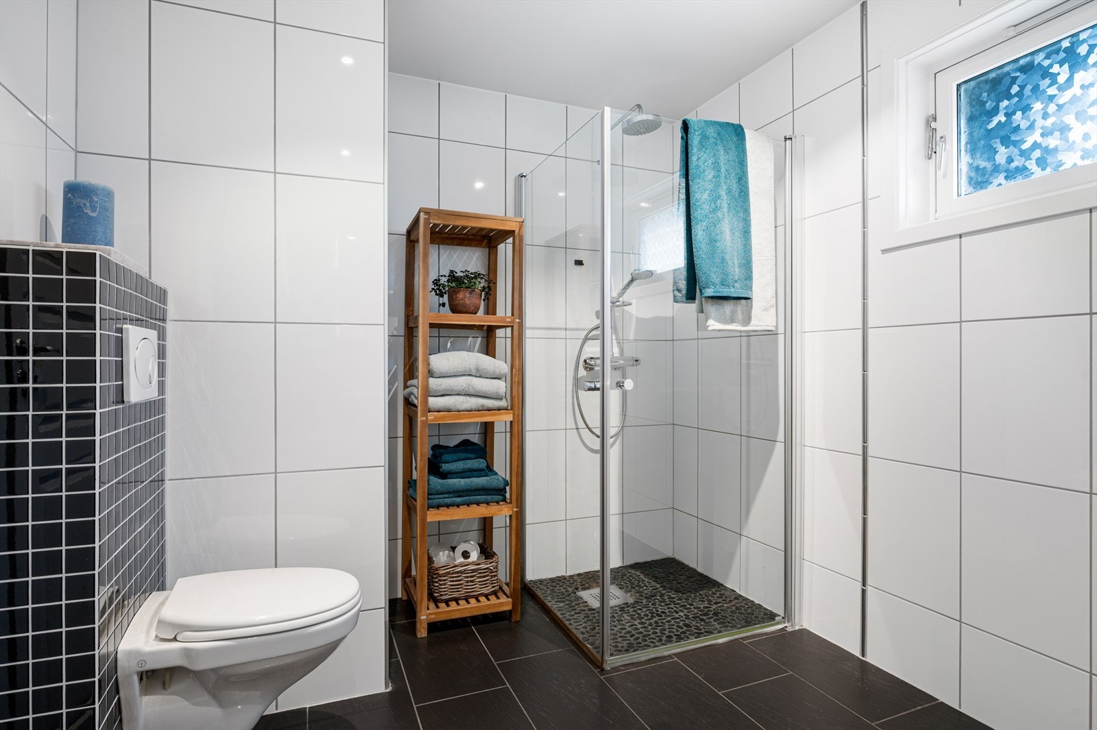 Badet er utstyrt med blant annet gulvvarme, innfellbare dusjdører, mekanisk avtrekk, servant, servantskap og veggmontert wc. Galleribilde