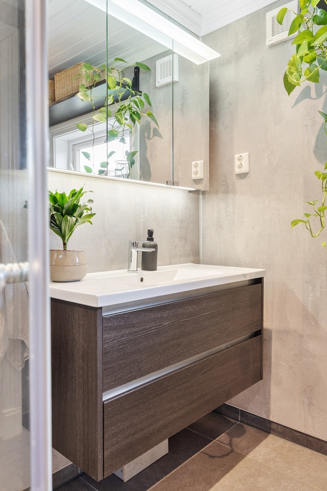 Innredningen har heldekkende servant over skuffeseksjon, matchende høyskap og et stort speilskap med belysning. Galleribilde