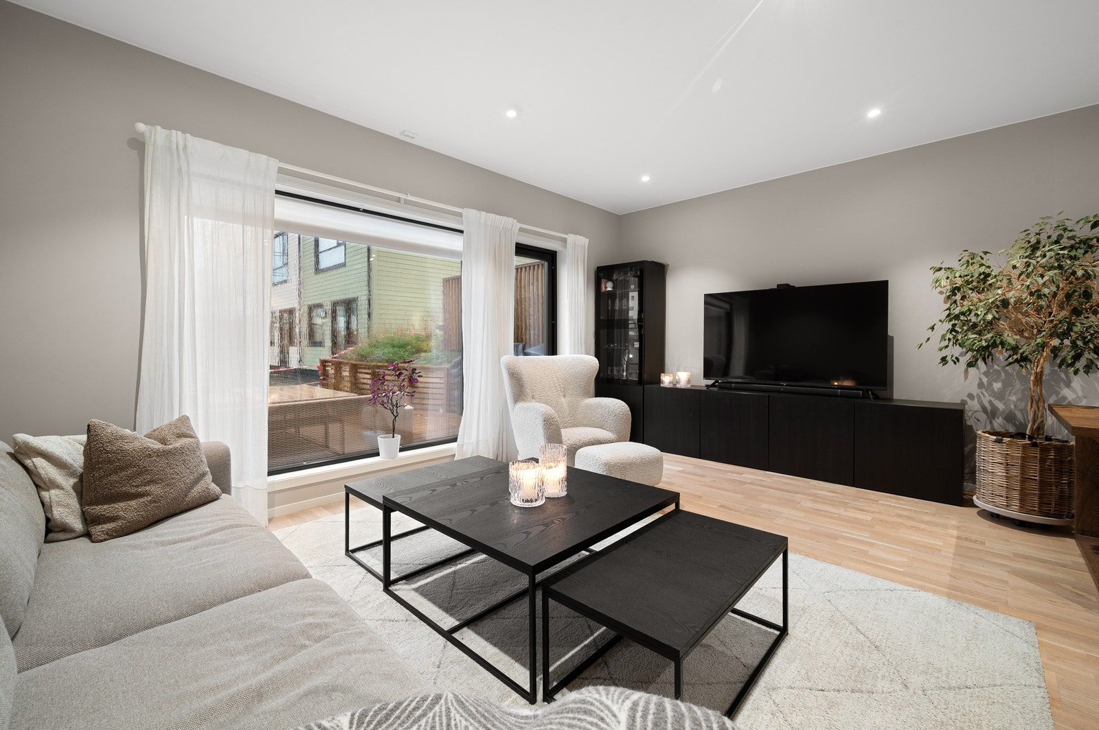 Lun og hyggelig stue med flere store vindusflater og tidsriktige farge- og materialvalg. Galleribilde