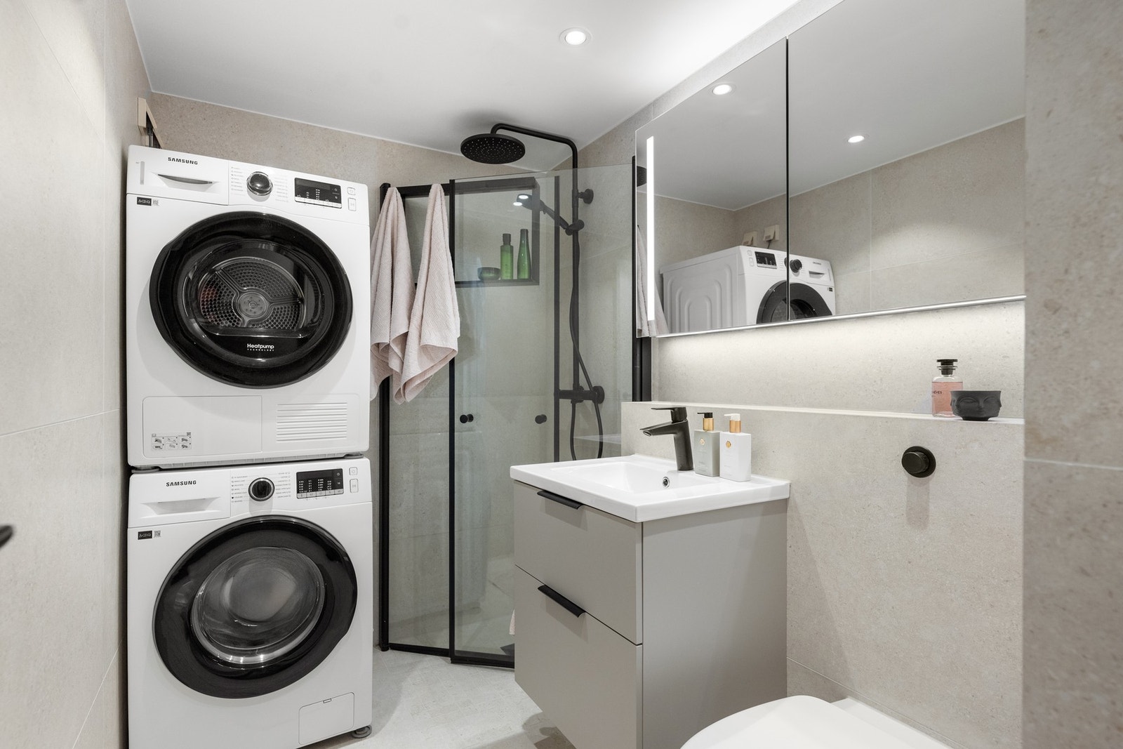 Pent baderom med servant, dusj, vegghengt toalett og opplegg for vaskemaskin/tørketrommel Galleribilde