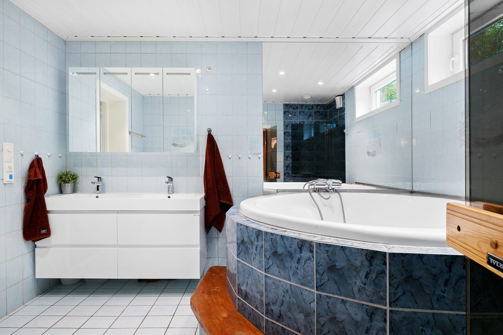 Bad fra byggeår med hjørnebadekar omkranset av blå fliser Galleribilde