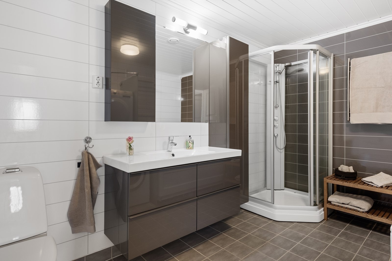 Badet er innredet med innredning med nedfelt servant, toalett, dusjkabinett, badekar og opplegg for vaskemaskin Galleribilde