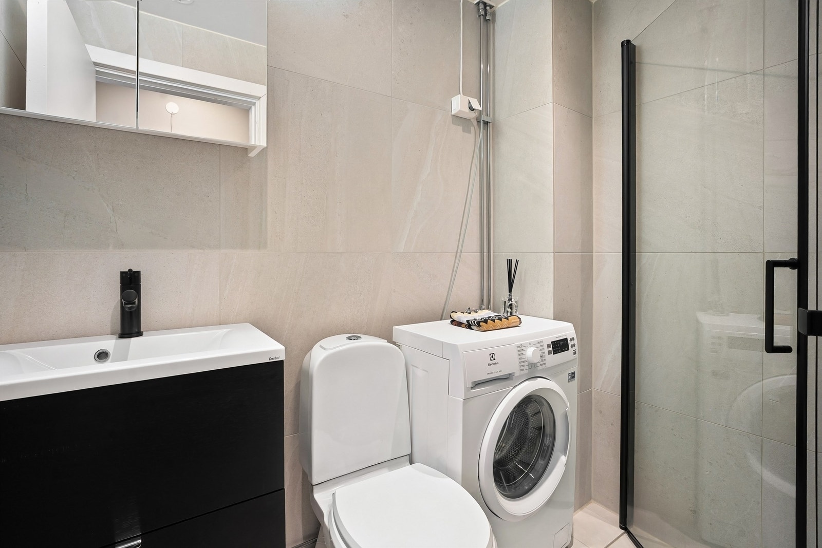 Baderom fra 2008 i regi av borettslaget med opplegg for vaskemaskin, flislagte gulvflater med gulvvarme, flislagte vegger og ned senket himling med downlights. Galleribilde